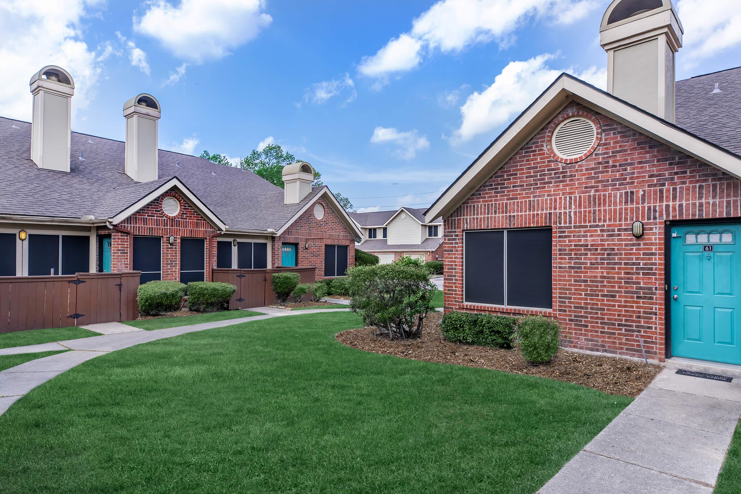 a large brick building with grass in front of a house