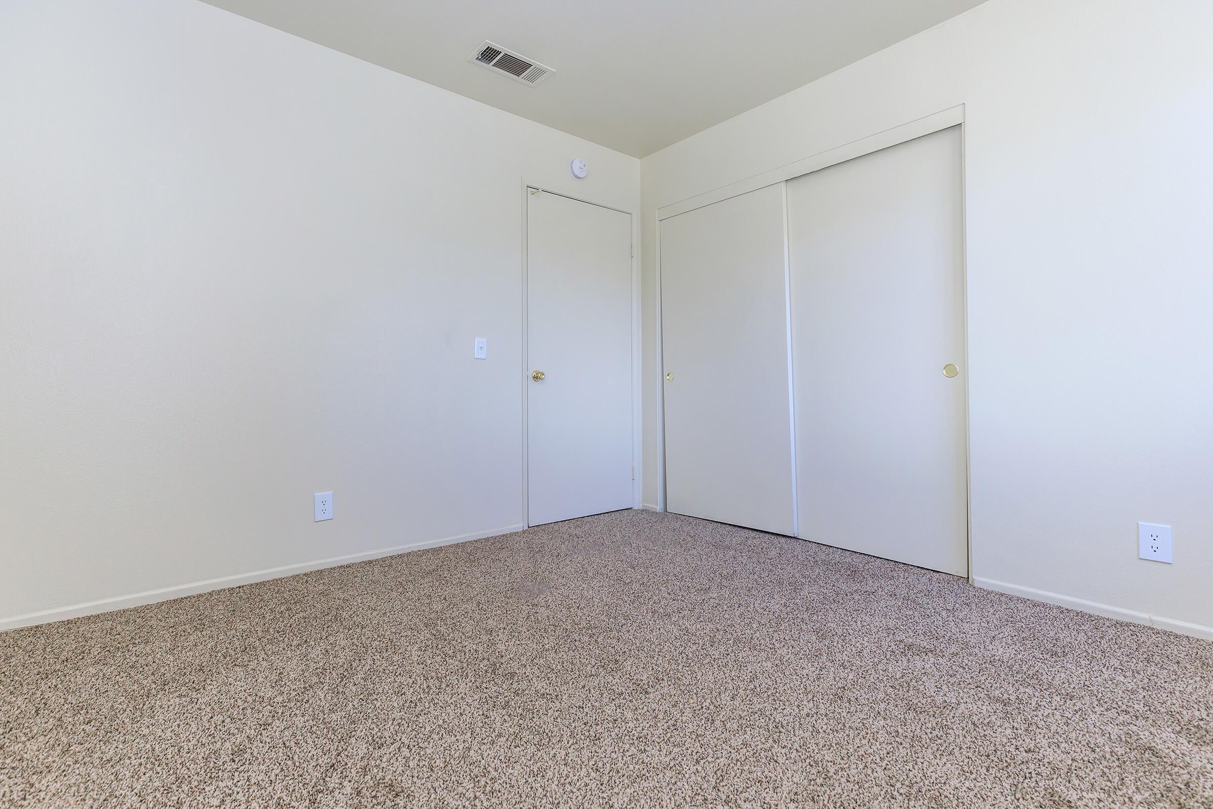 Vacant bedroom with carpet and sliding closet doors