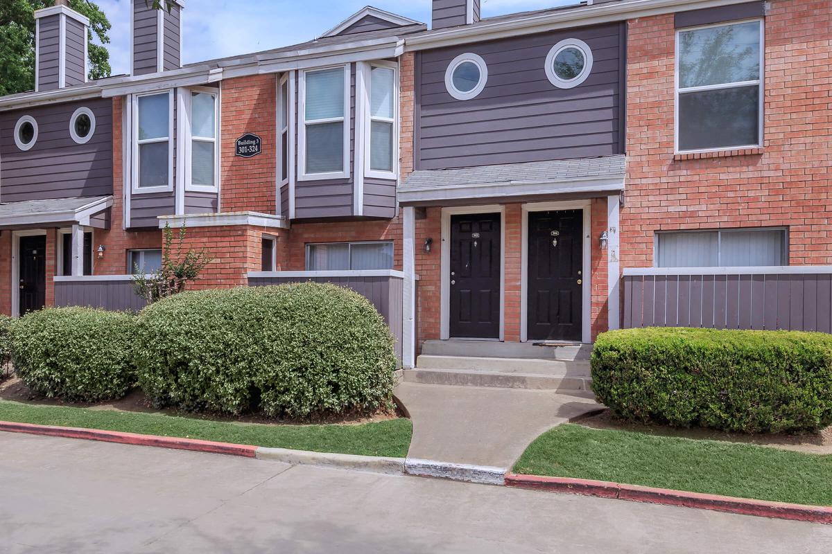 a house with bushes in front of a brick building