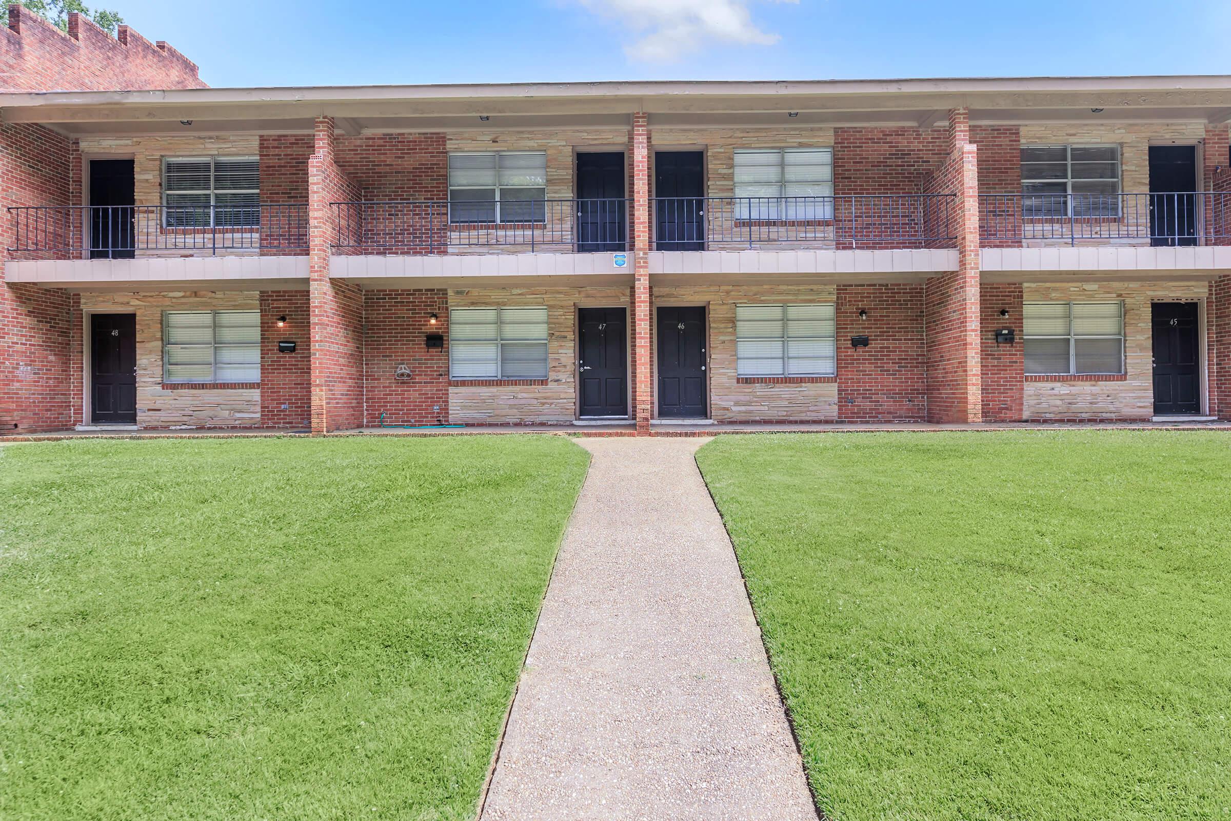 a large lawn in front of a brick building