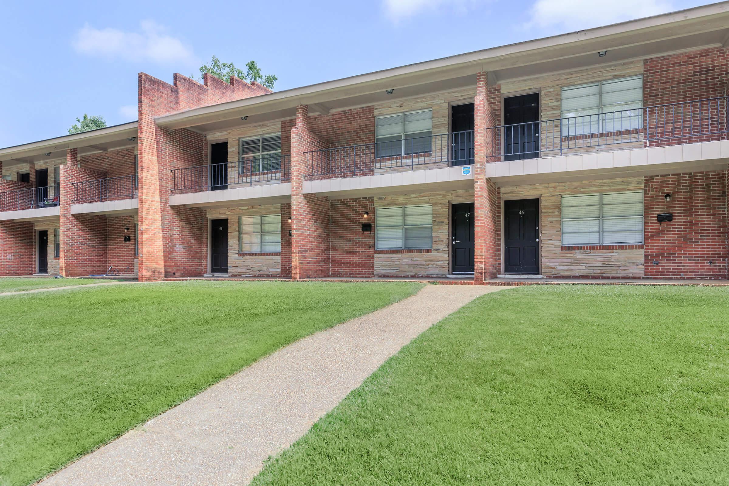 a large brick building with grass in front of a house