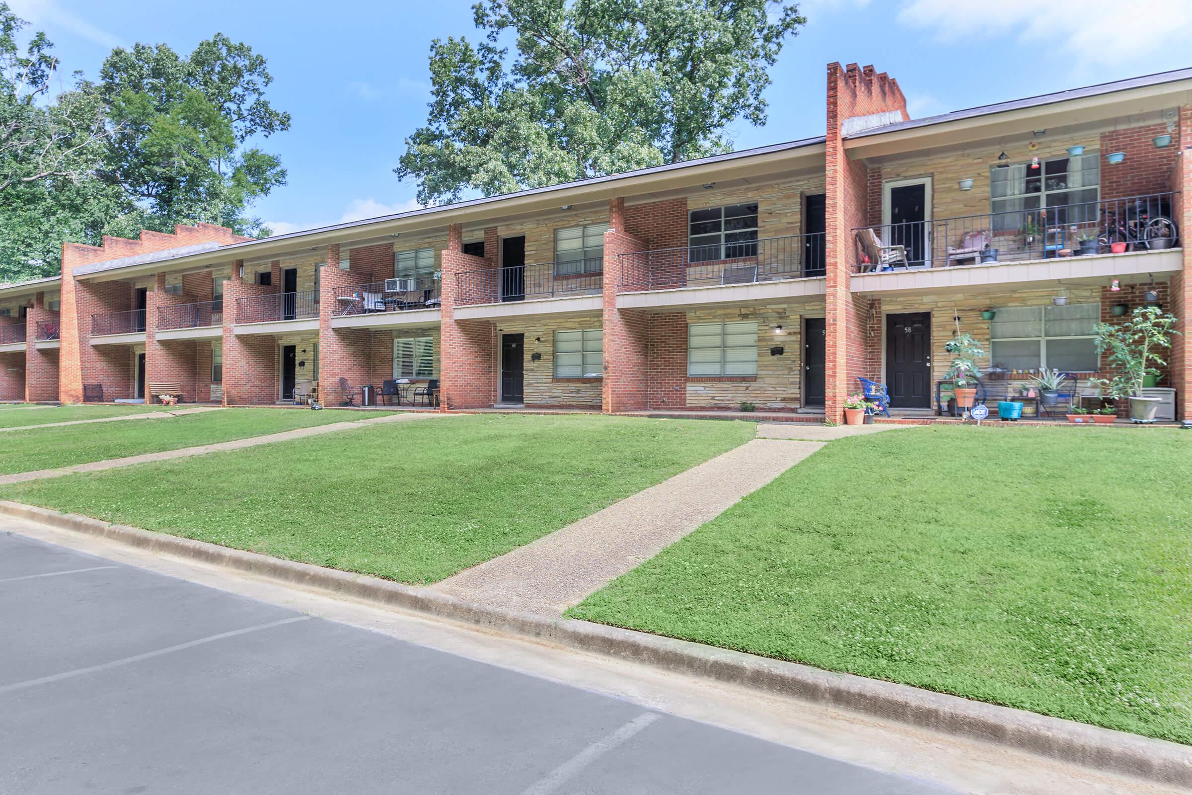 a large brick building with grass in front of a house