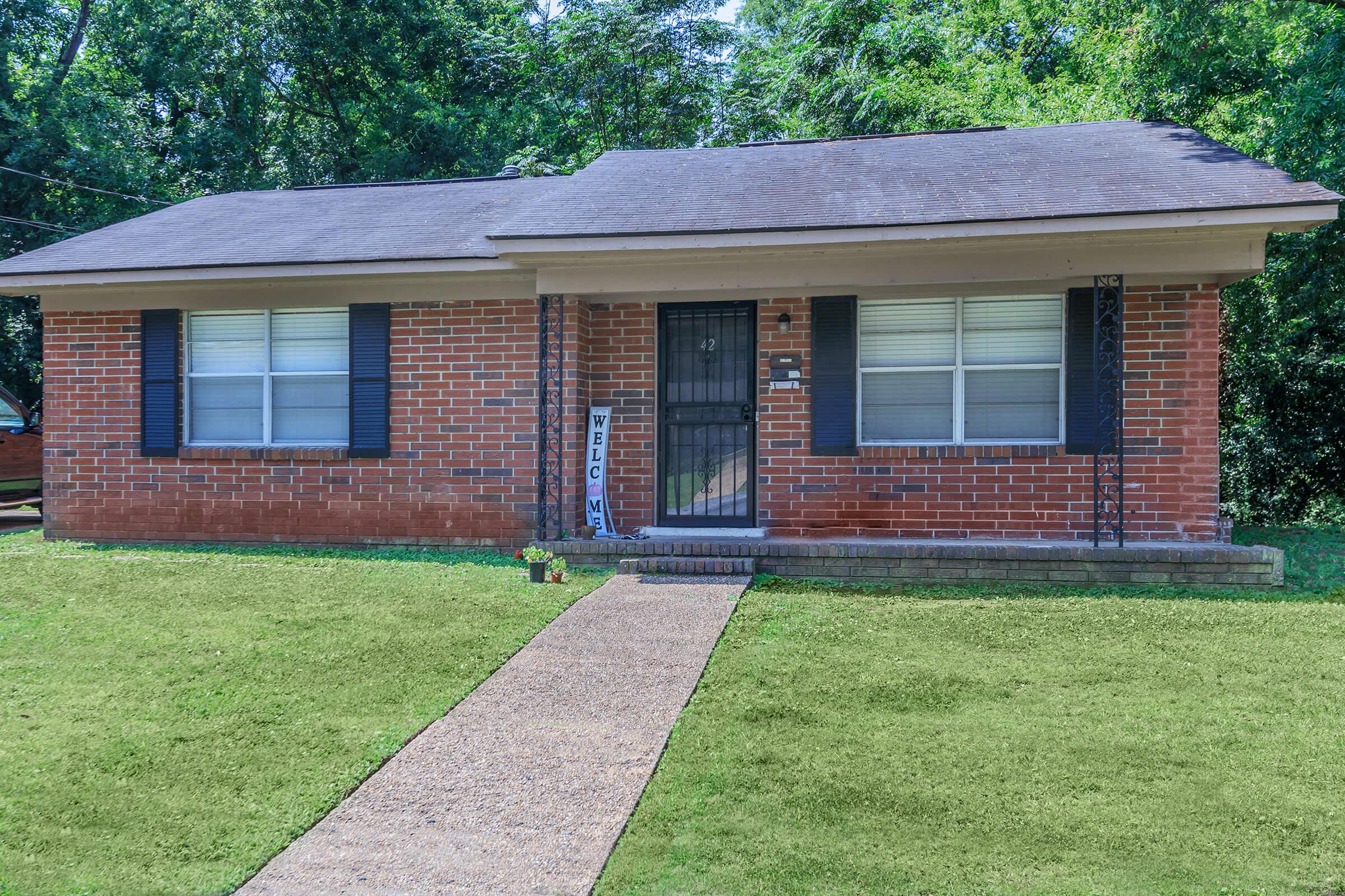 a house with a lawn in front of a brick building