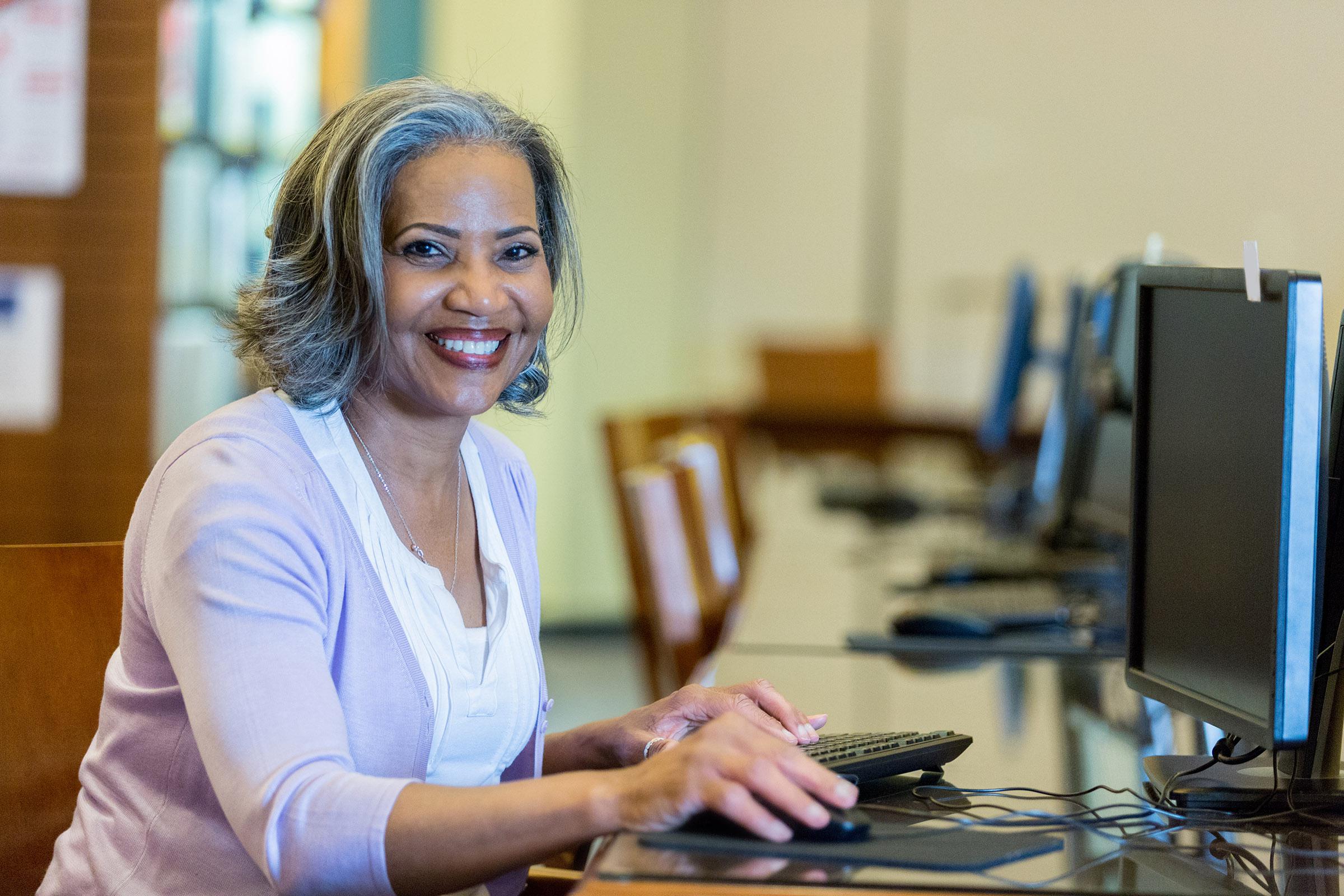 a woman sitting at a table using a laptop computer