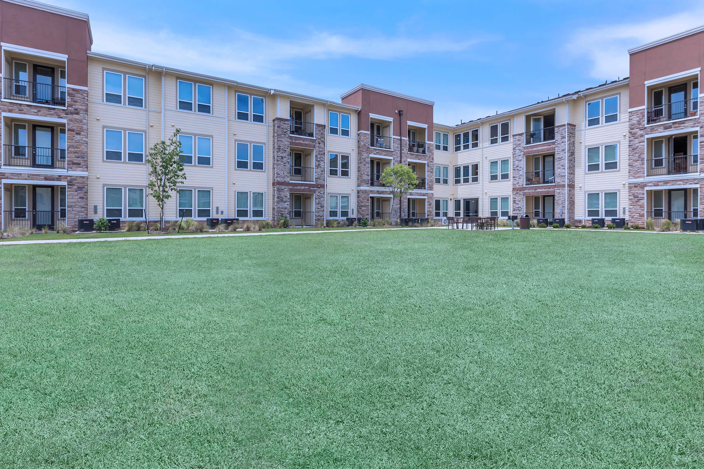 a large brick building with green grass