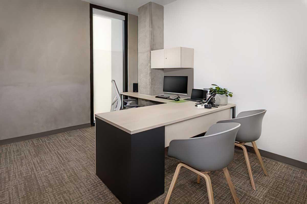 Modern office space featuring a desk with a computer, a chair, and two additional chairs.