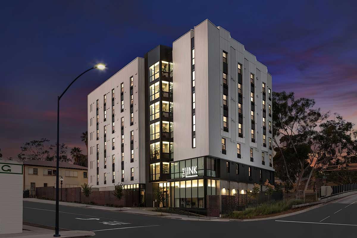 Modern multi-story building at dusk, featuring a sleek design with white and black panels.