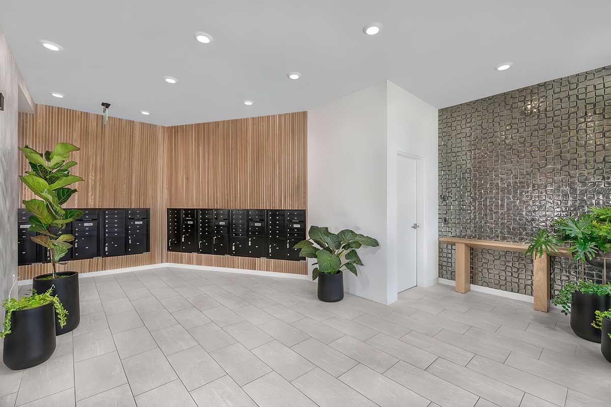 Modern lobby interior featuring mailbox units mounted on a wooden wall, with a textured stone accent wall on the right.