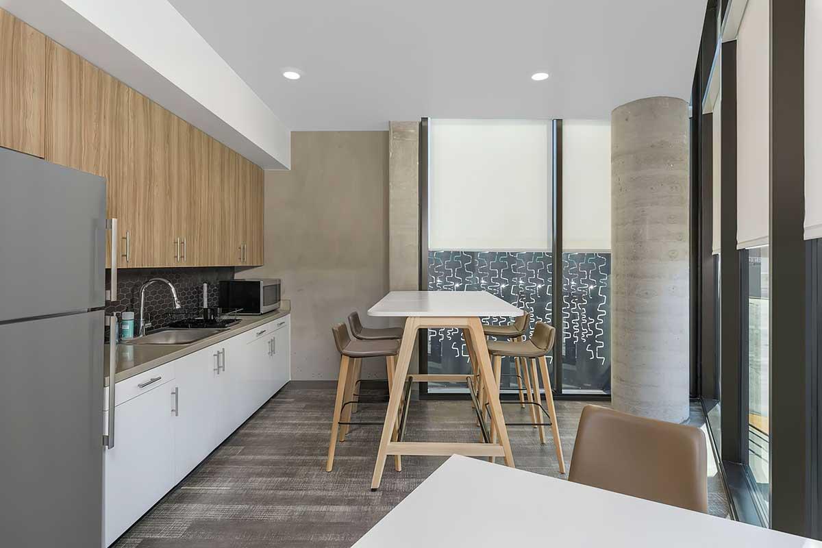 A modern kitchen with wooden cabinetry and sleek white countertops.