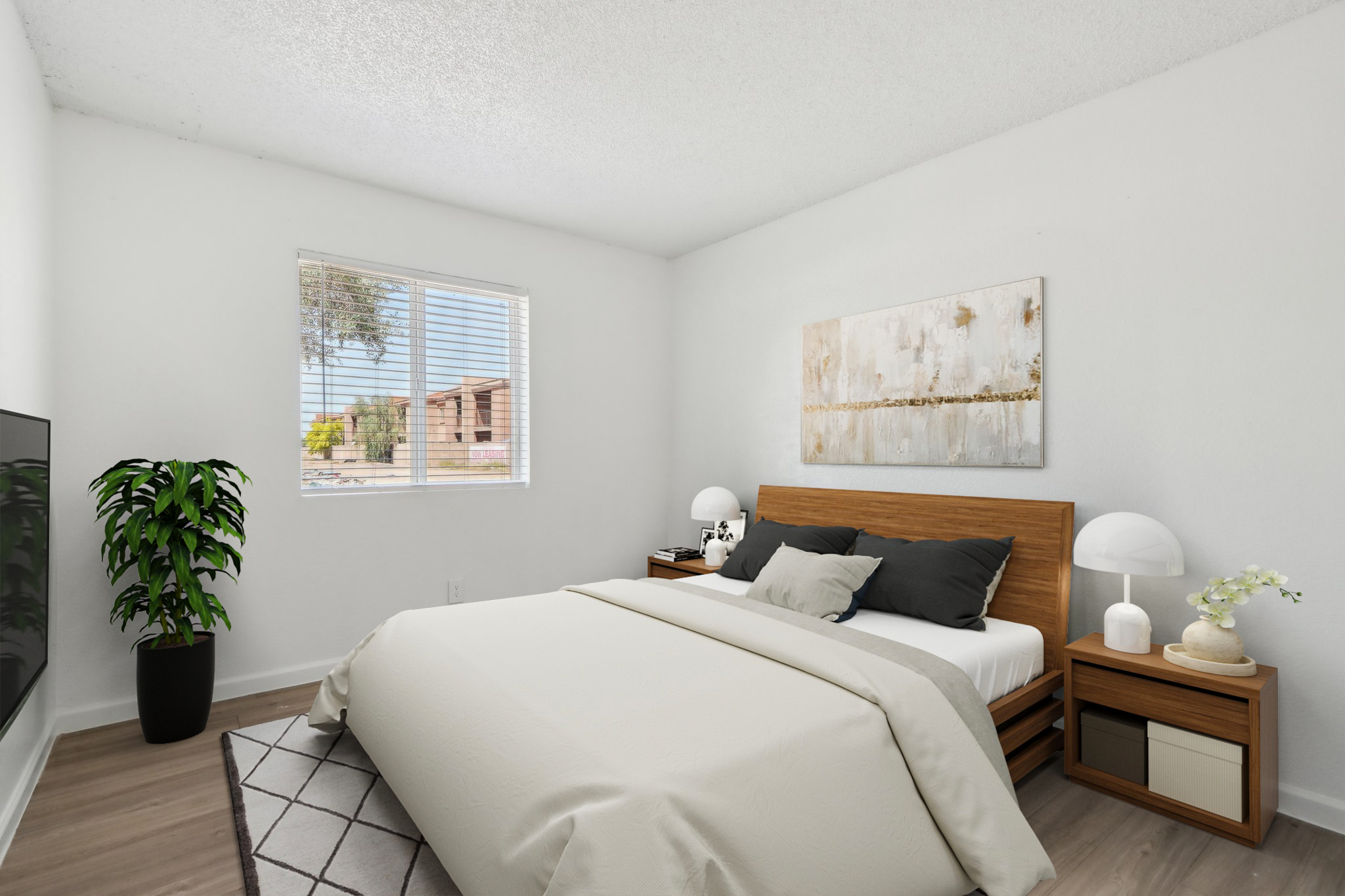 A minimalistic bedroom featuring a wooden bed with a light-colored duvet, two decorative pillows, and bedside lamps. There's a window with blinds allowing natural light in, a potted plant, a light-colored rug, and a piece of abstract art on the wall. A television is visible in the corner.