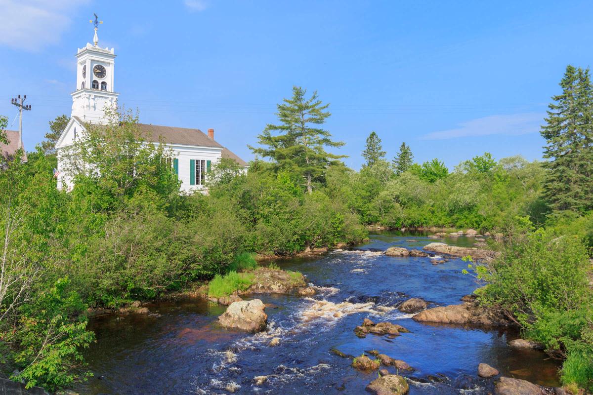 a small house in a body of water surrounded by trees