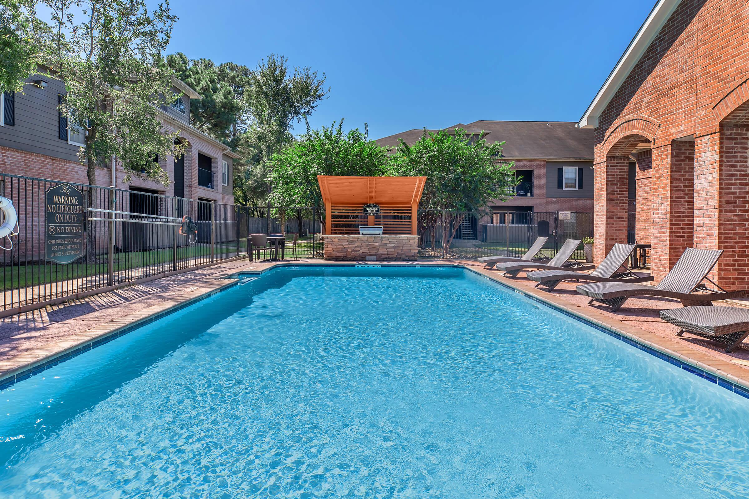 a house with a pool in front of a brick building