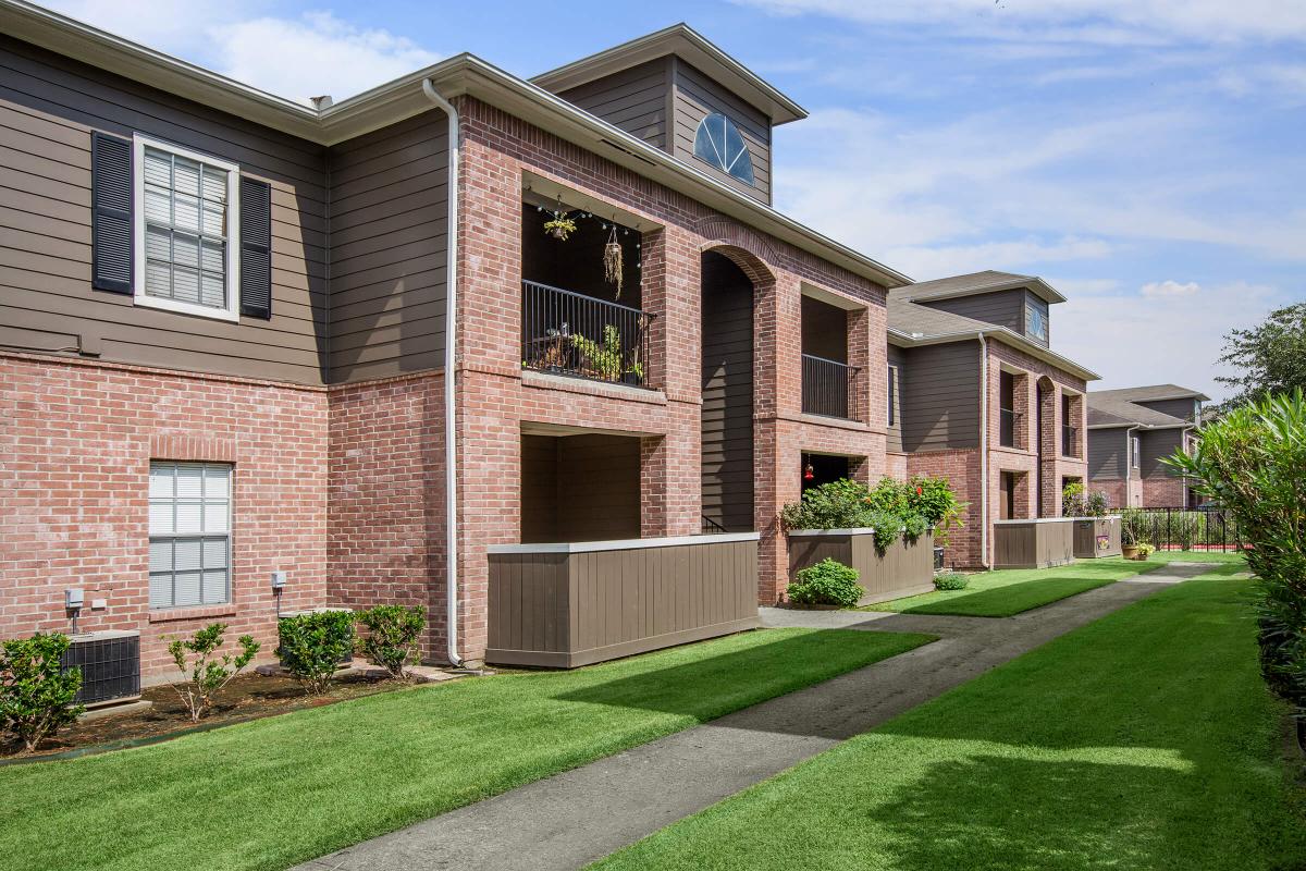 a large brick building with grass in front of a house