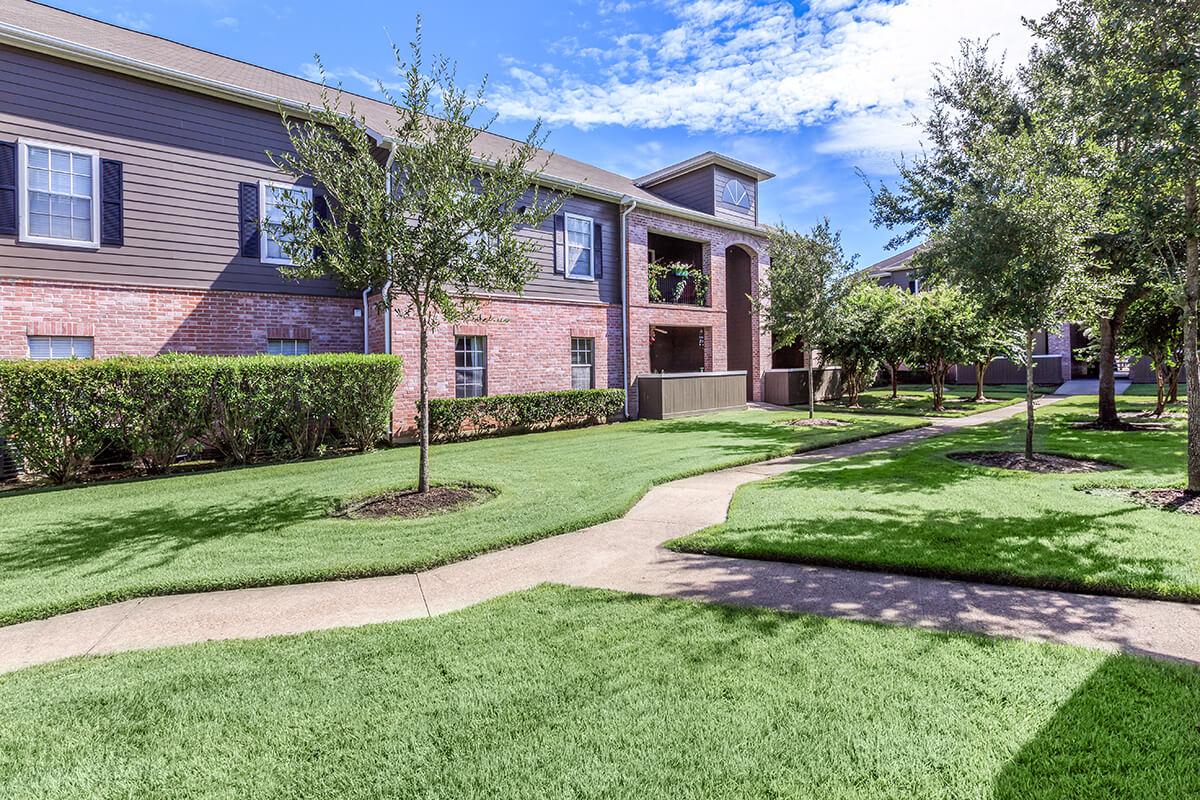 a house with a lawn in front of a brick building