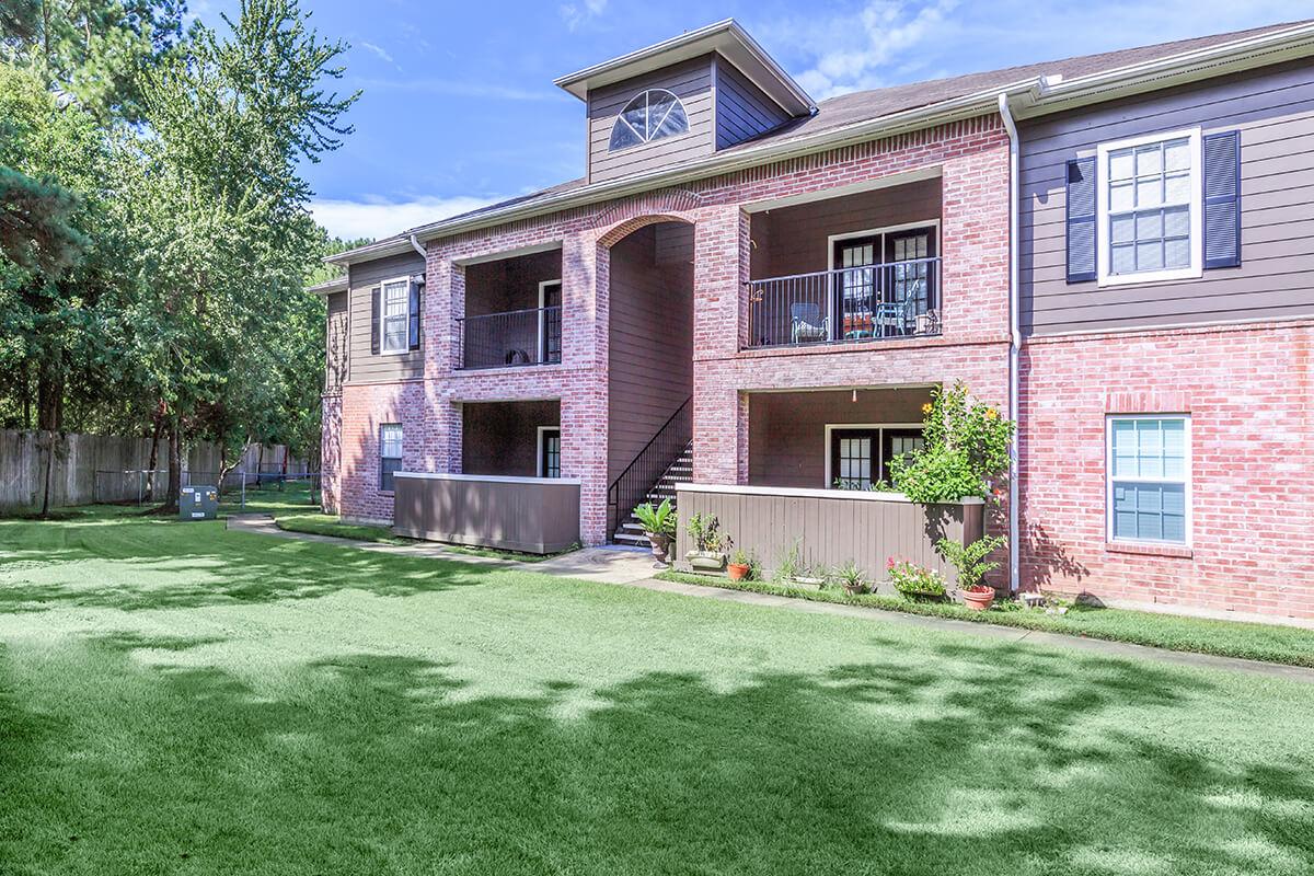 a large brick building with grass in front of a house