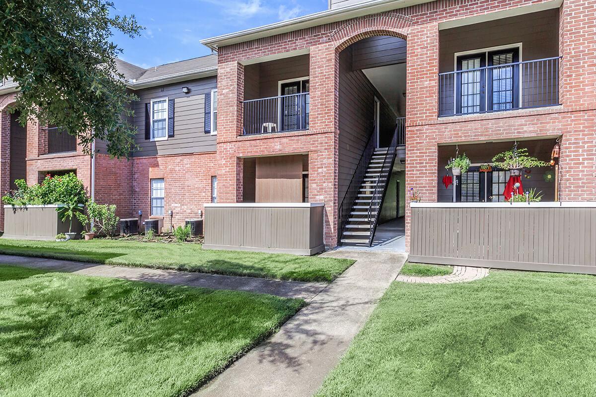 a large brick building with grass in front of a house