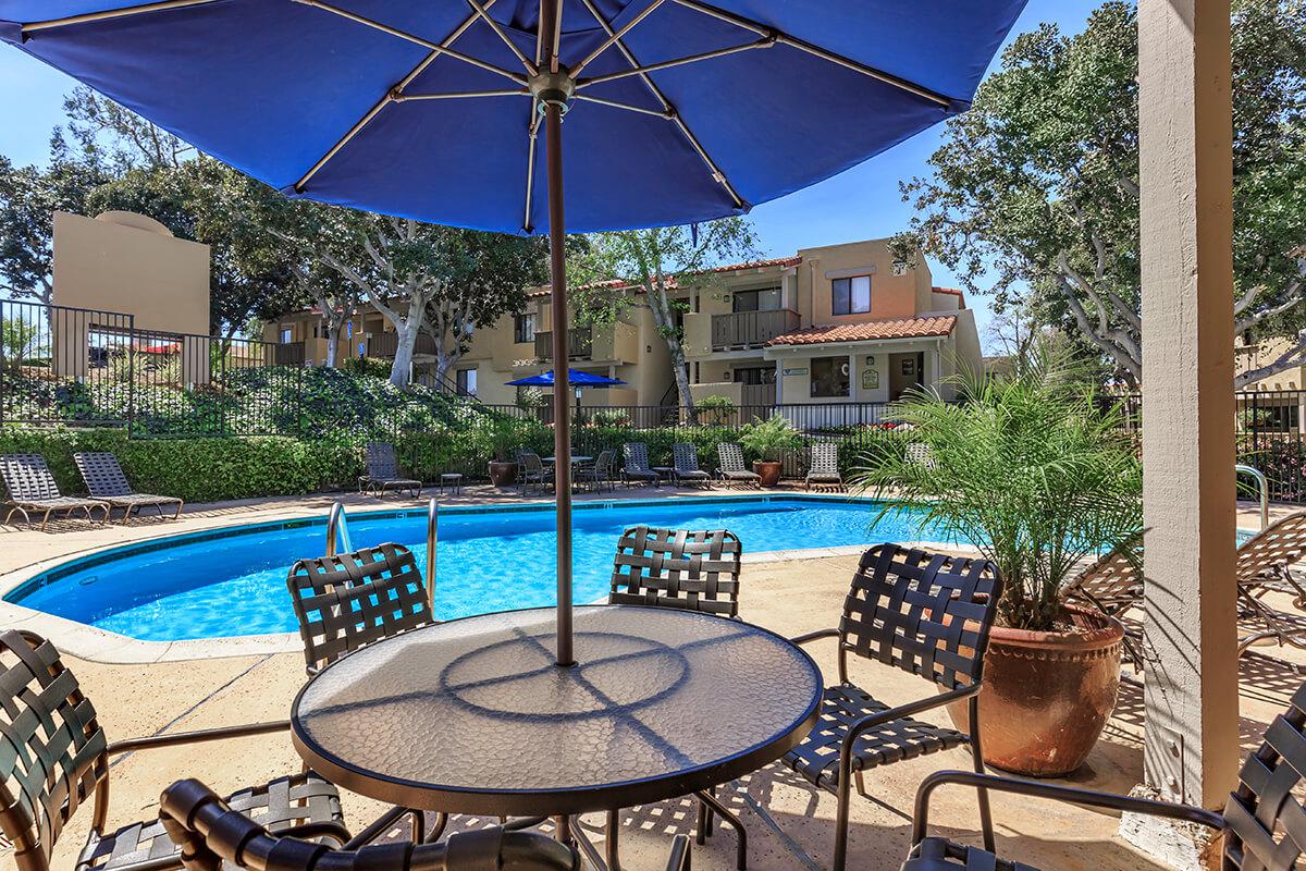 A table and chairs next to the community pool