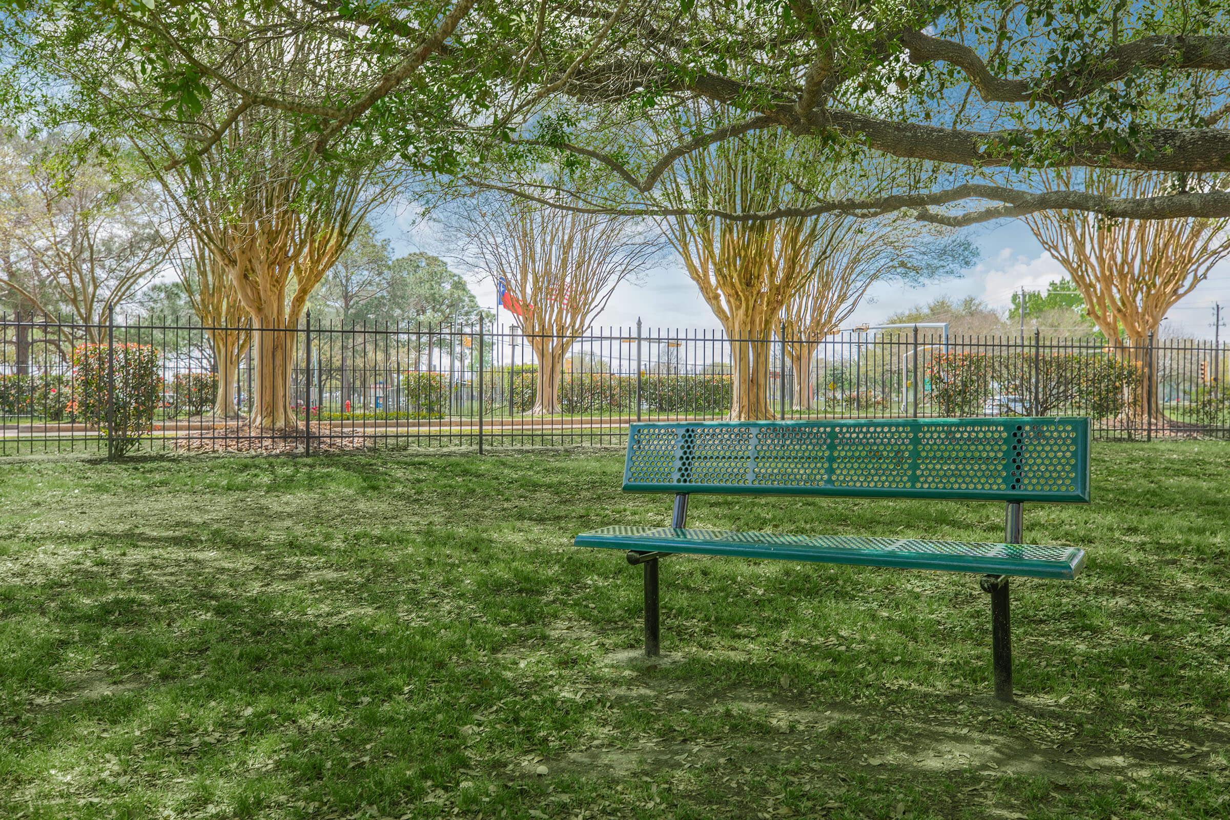 a green park bench sitting in front of a fence