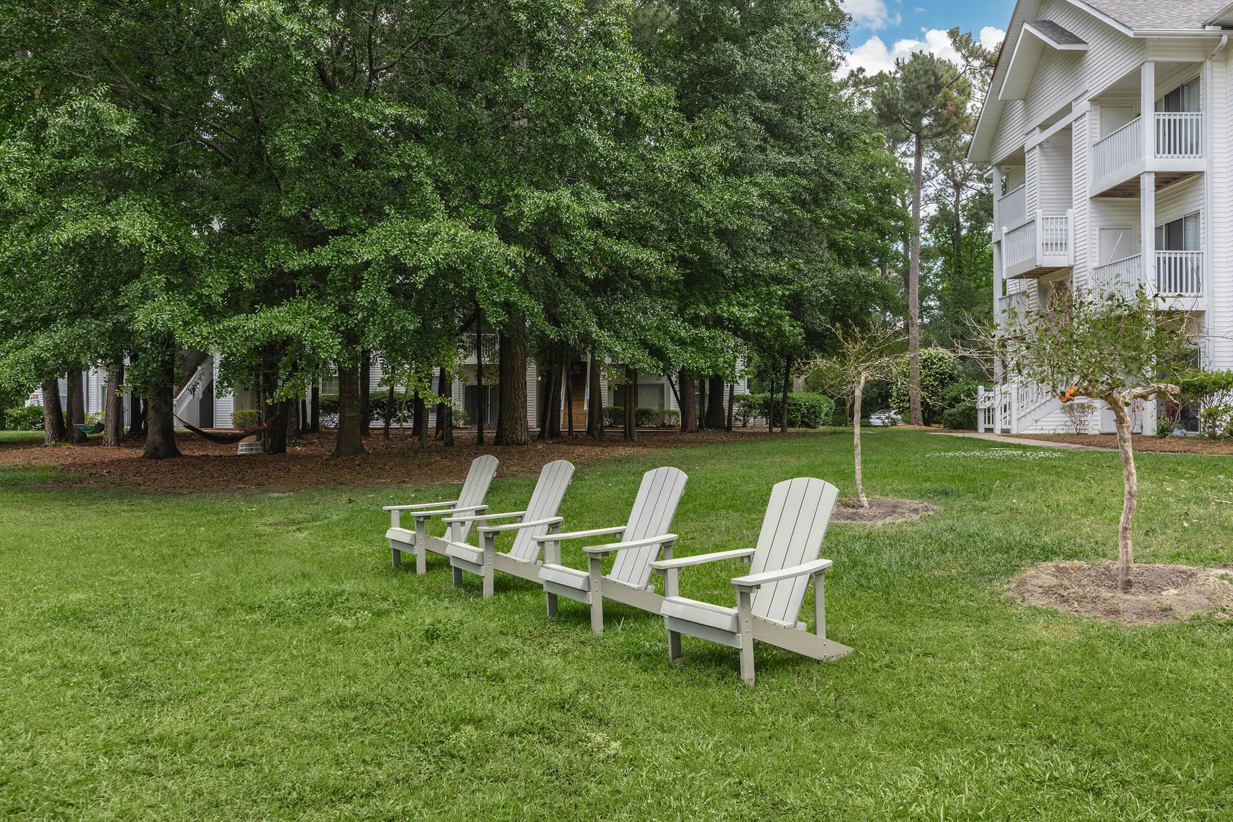 a couple of lawn chairs sitting on top of a grass covered field