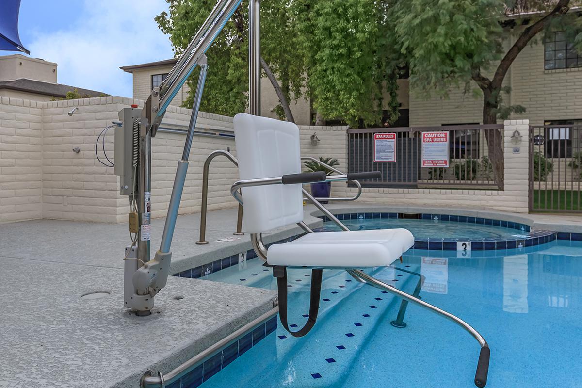 A pool lift chair positioned next to a swimming pool, designed for accessibility.