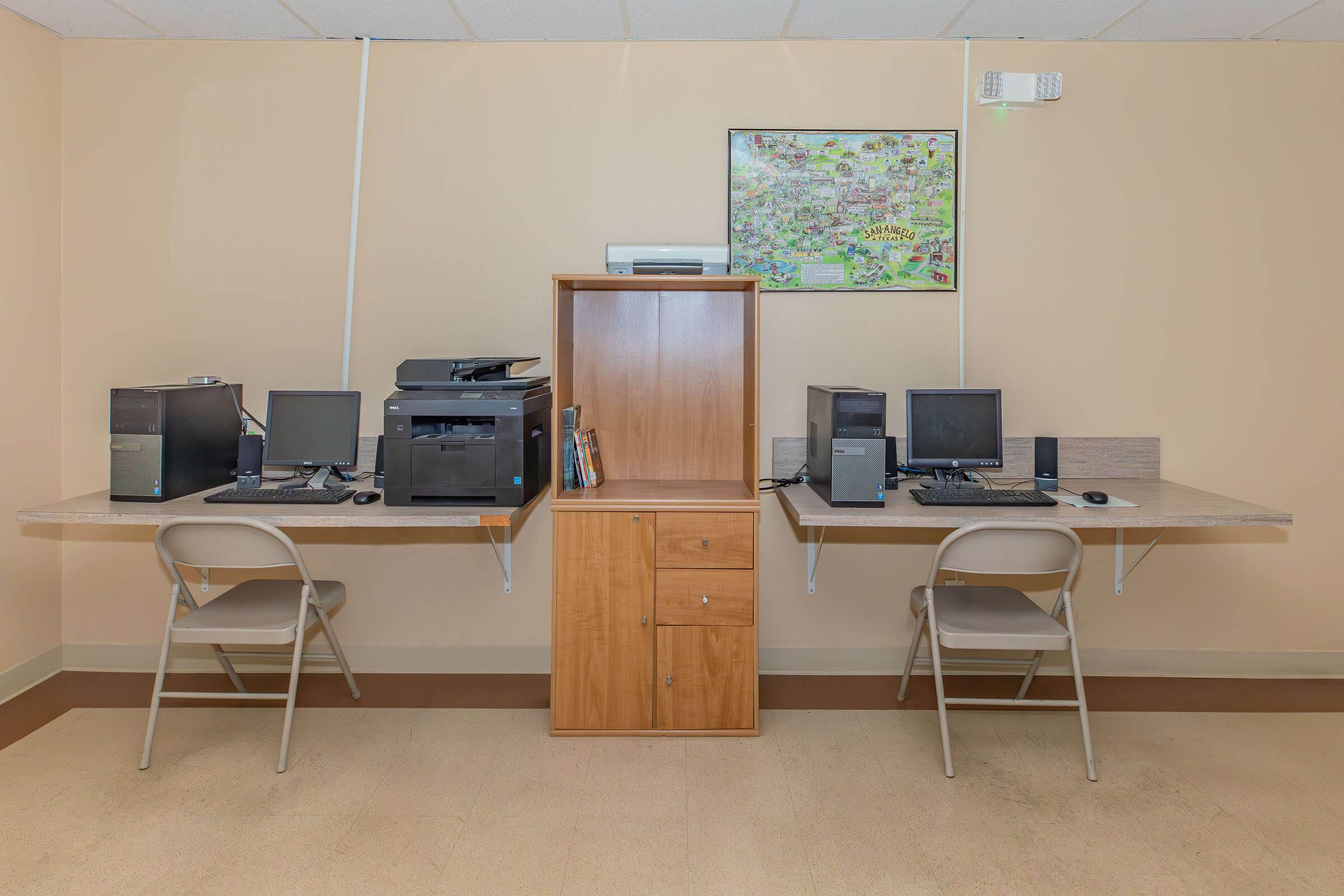 a desk with a computer and a chair in a room