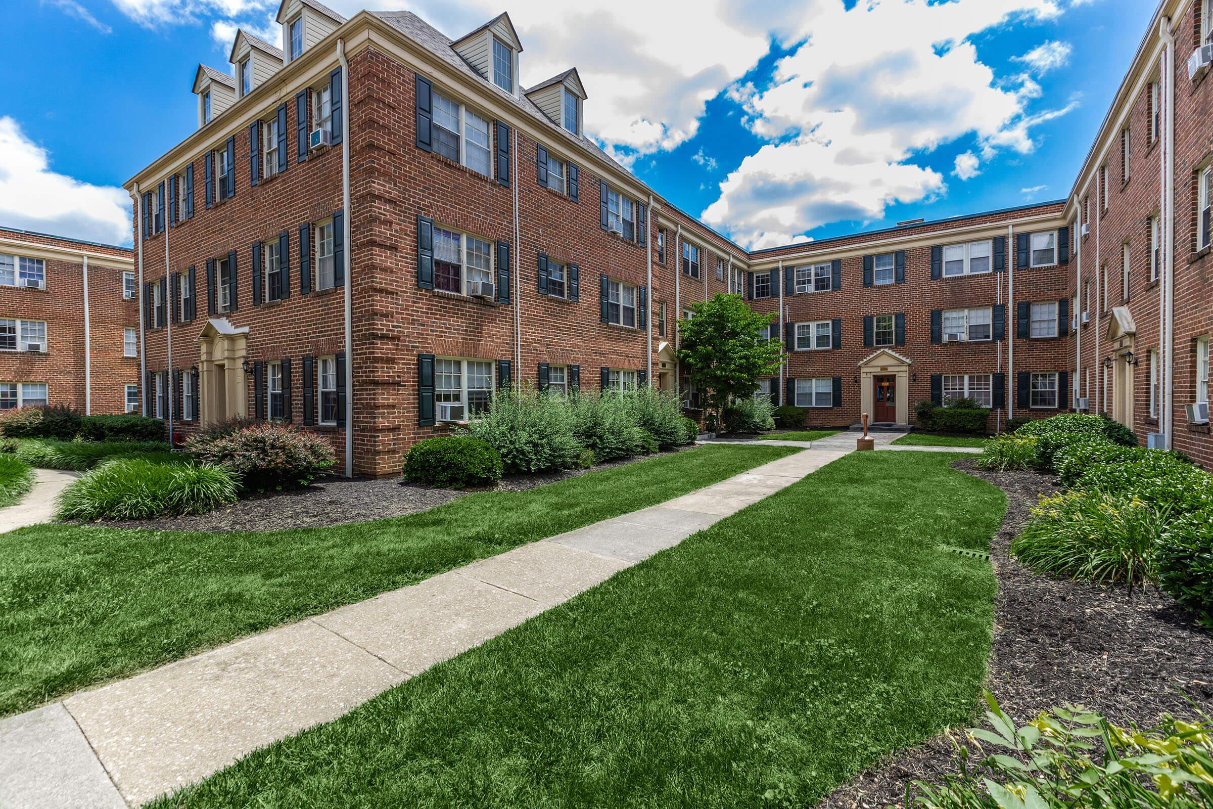 a large brick building with grass in front of a house