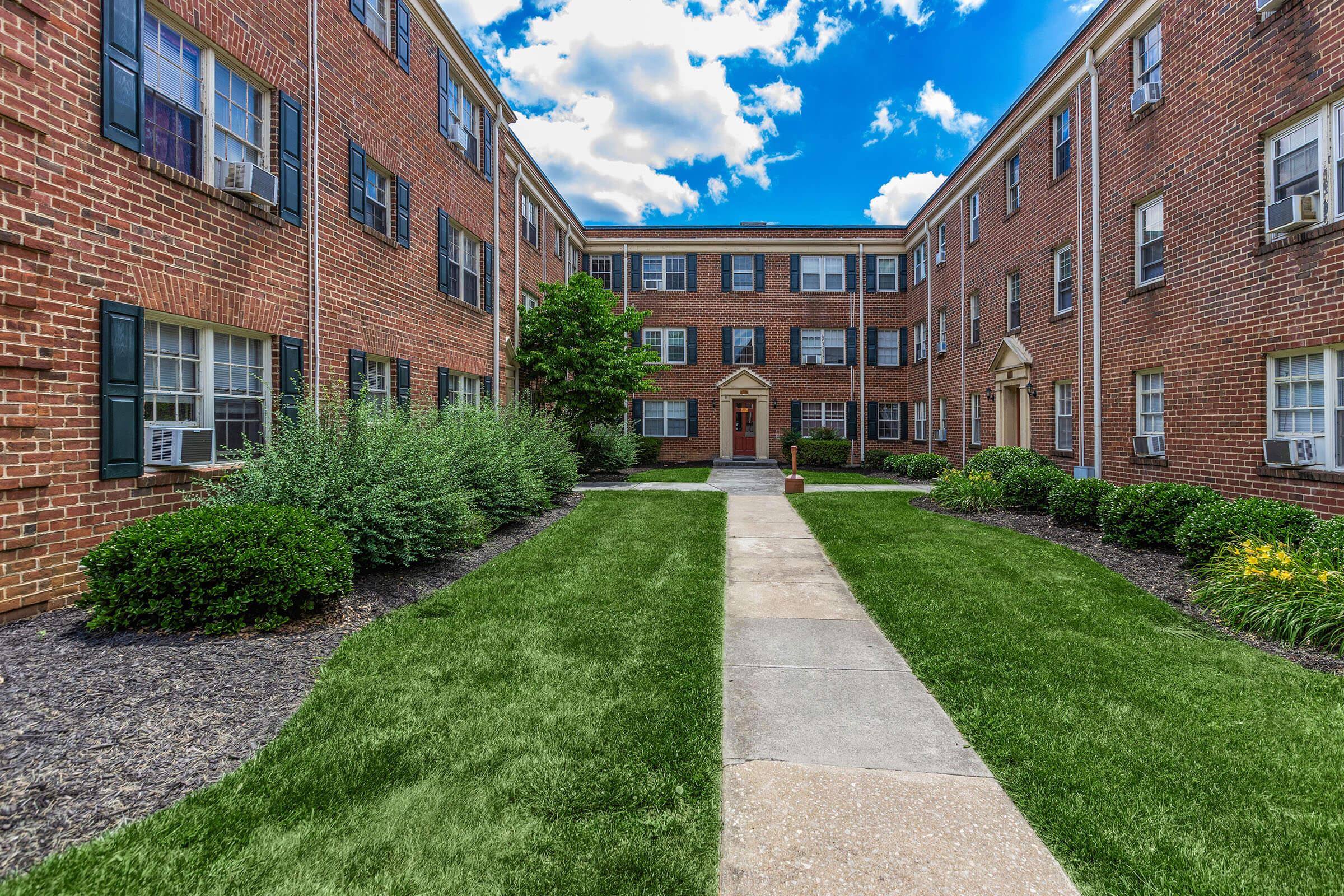 a large brick building with grass in front of a house