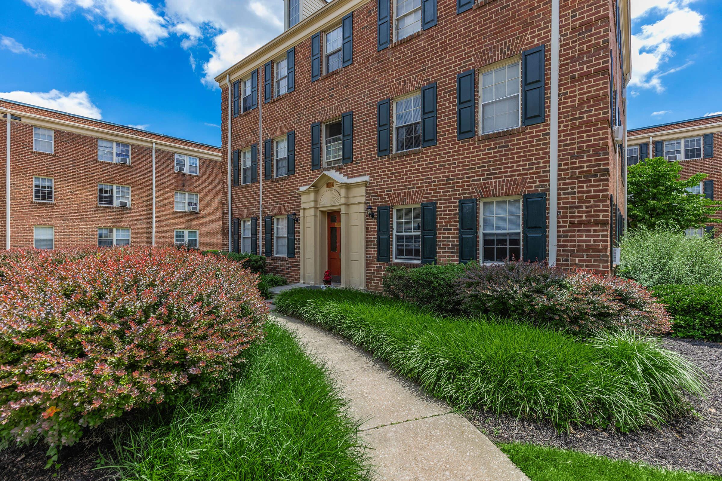 a large brick building with grass in front of a house