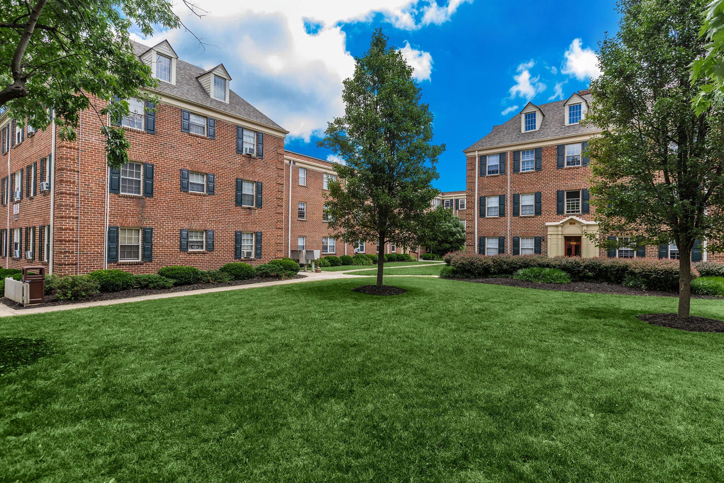 a large brick building with green grass in front of a house