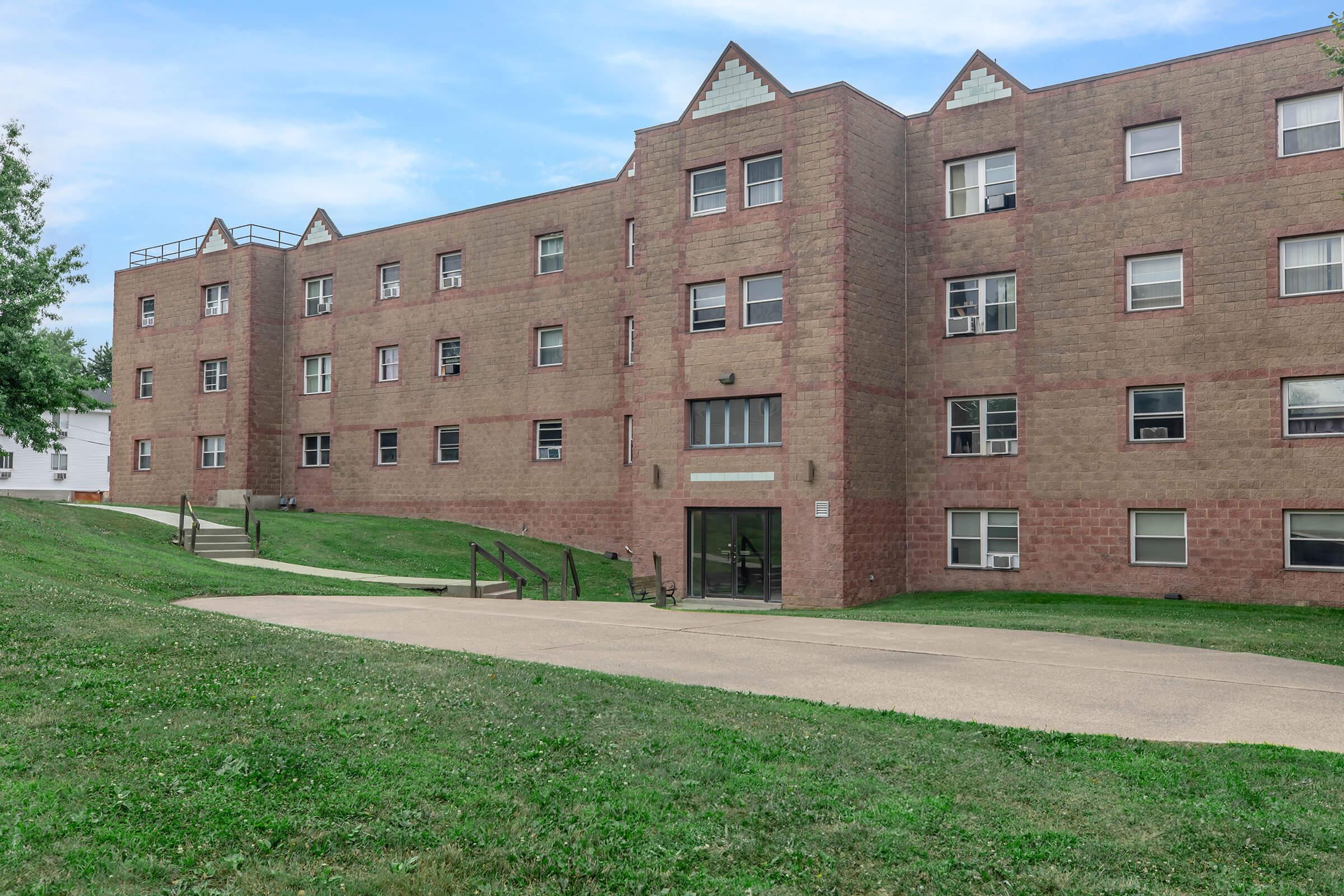 a large brick building with a grassy field