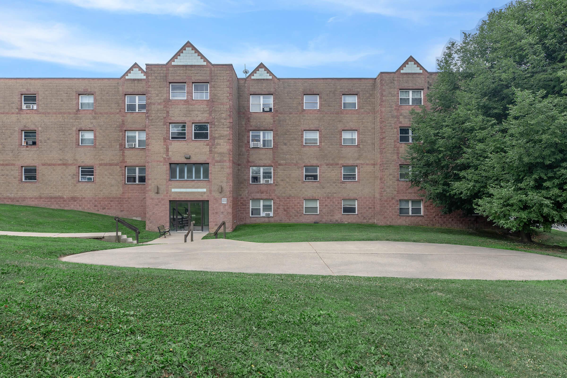 a large brick building with a grassy field