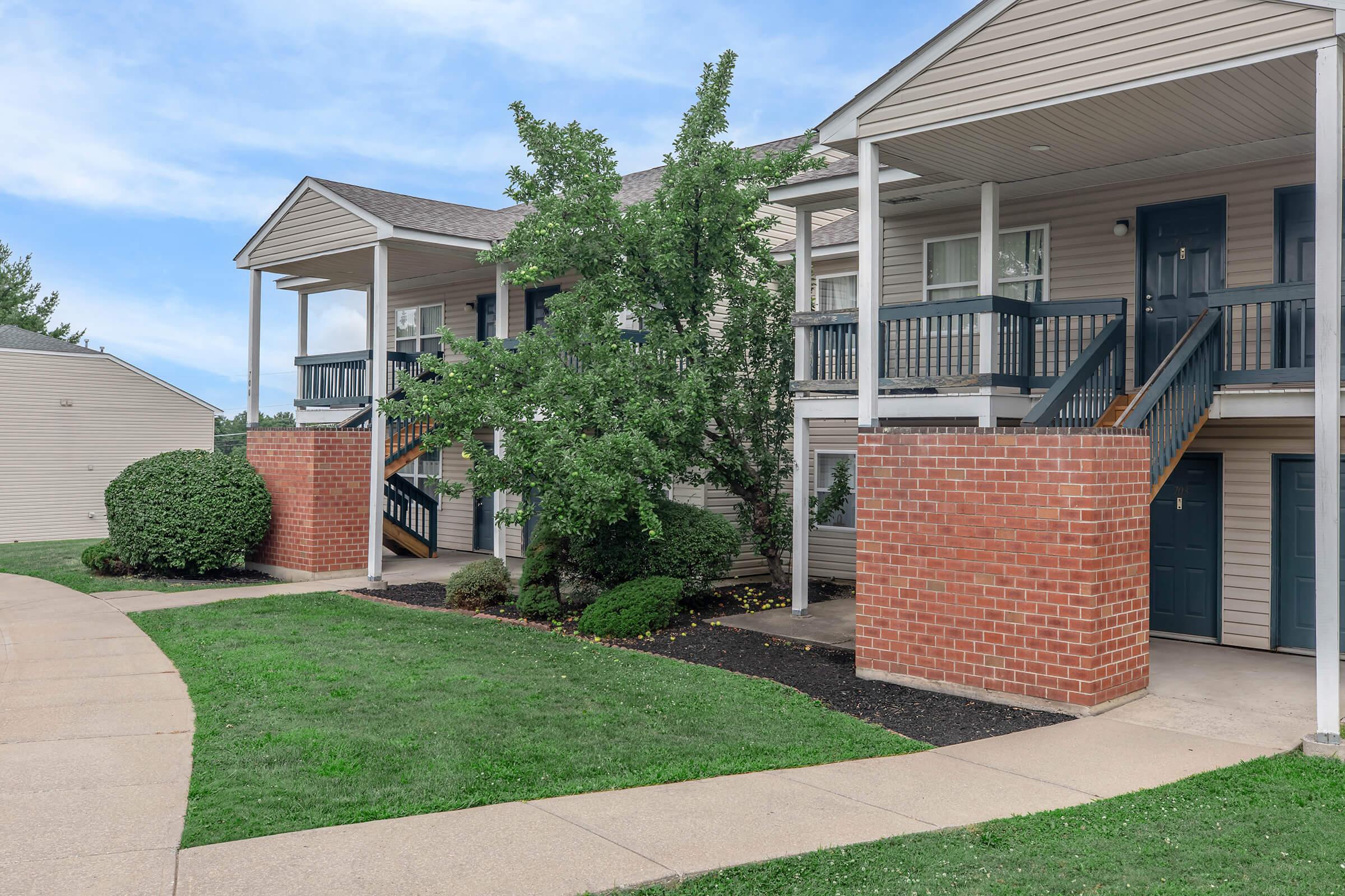 a house with a lawn in front of a brick building