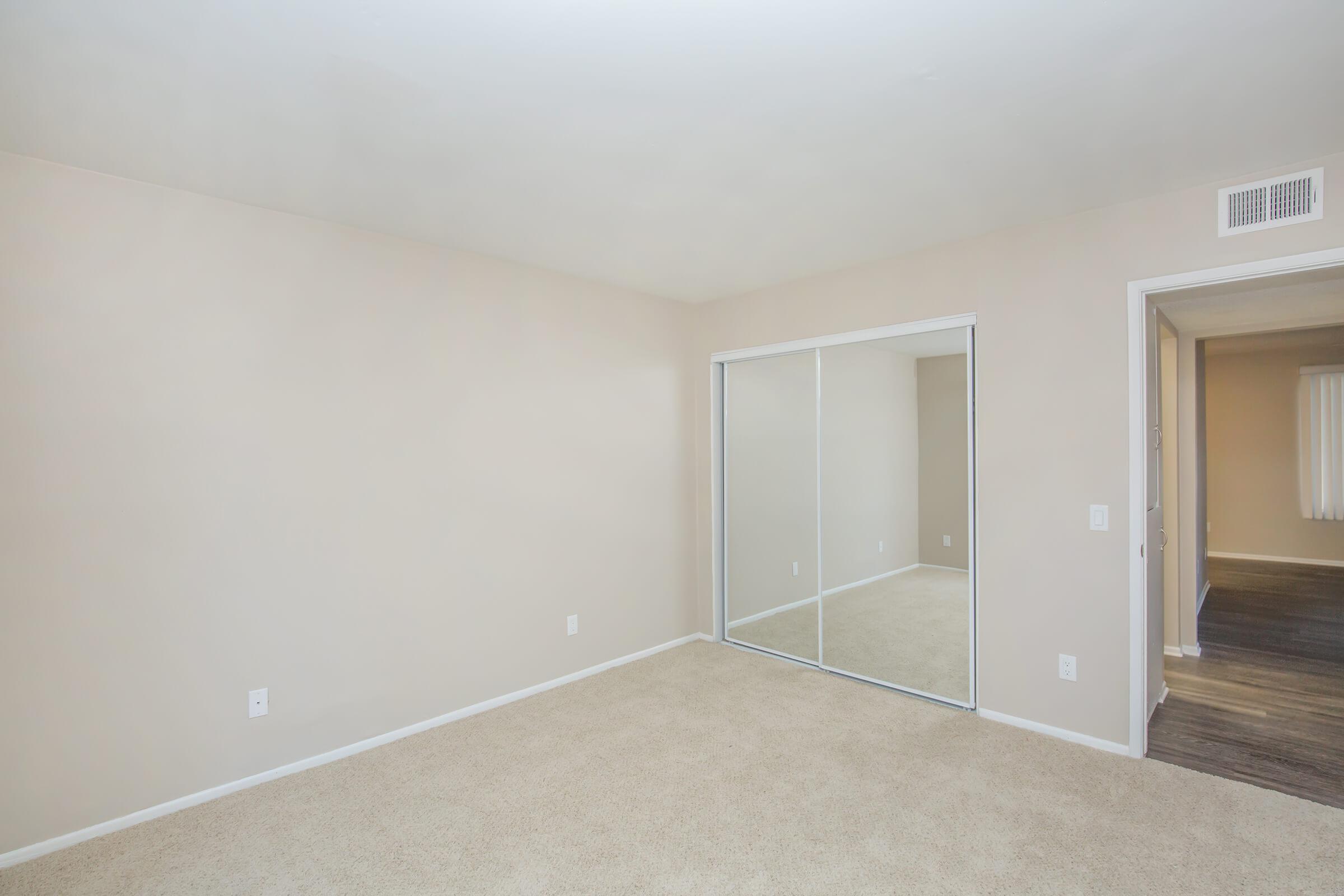 Carpeted bedroom with sliding mirror glass closet doors