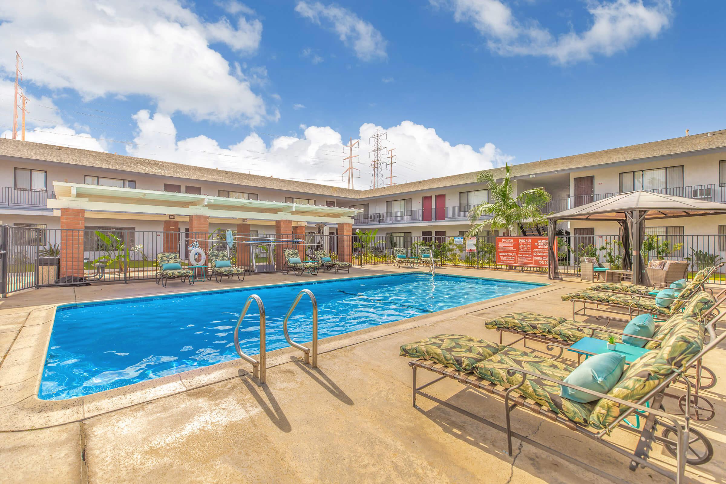 Miramar Apartments community pool with blue pillows on chairs