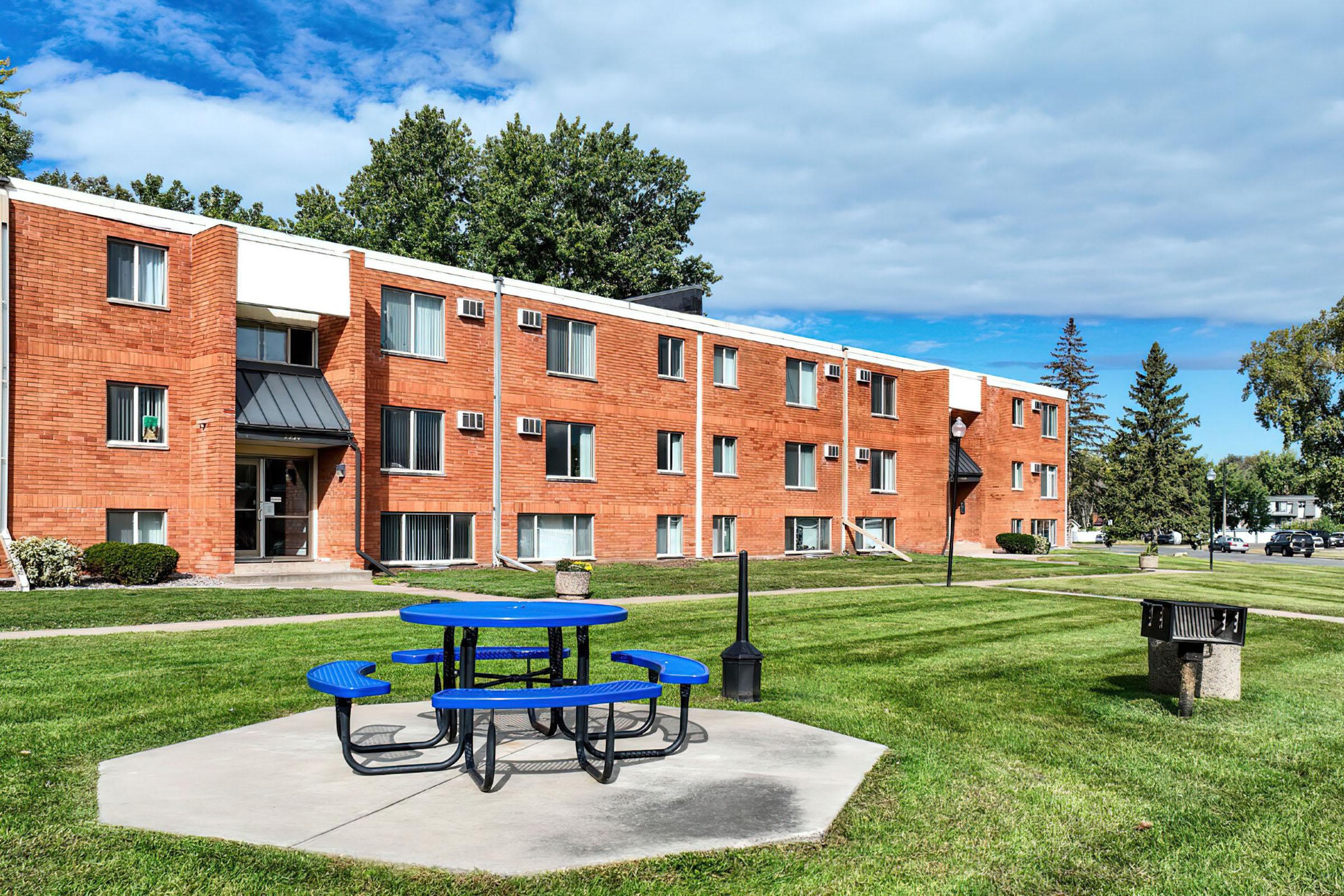 an empty park bench sitting in front of a brick building