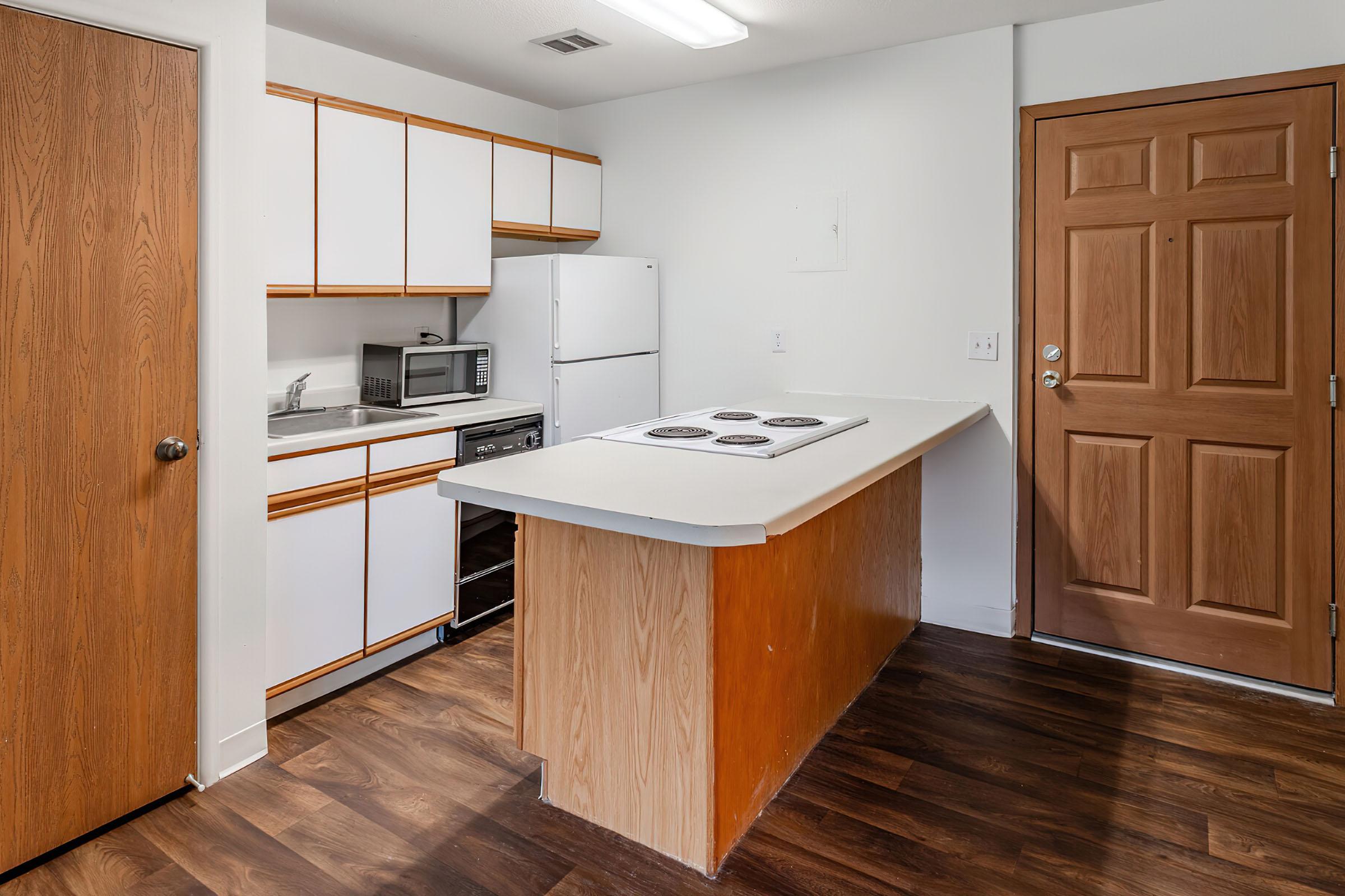 a kitchen with wooden cabinets and a wood floor