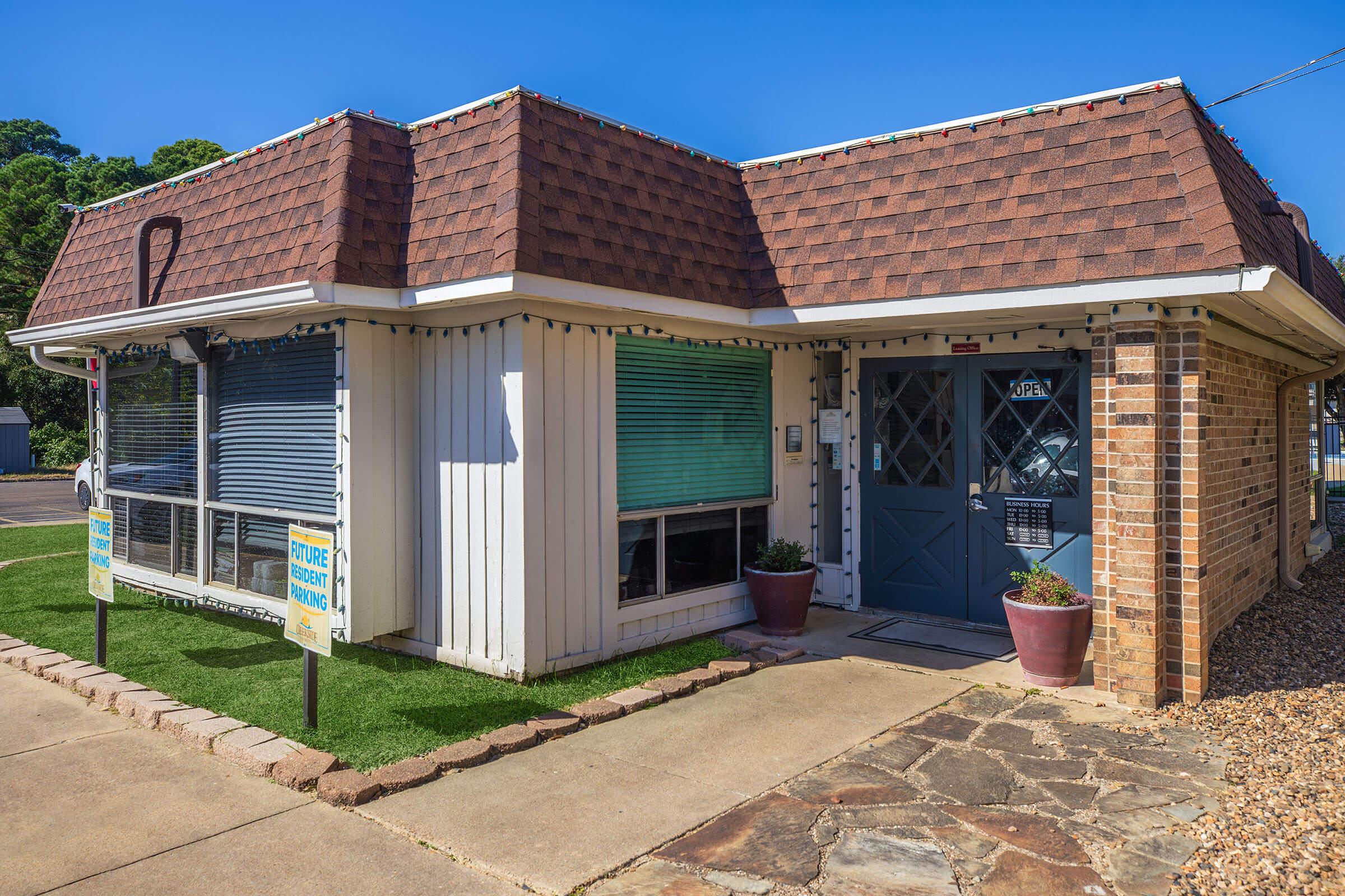 a house with a lawn in front of a brick building