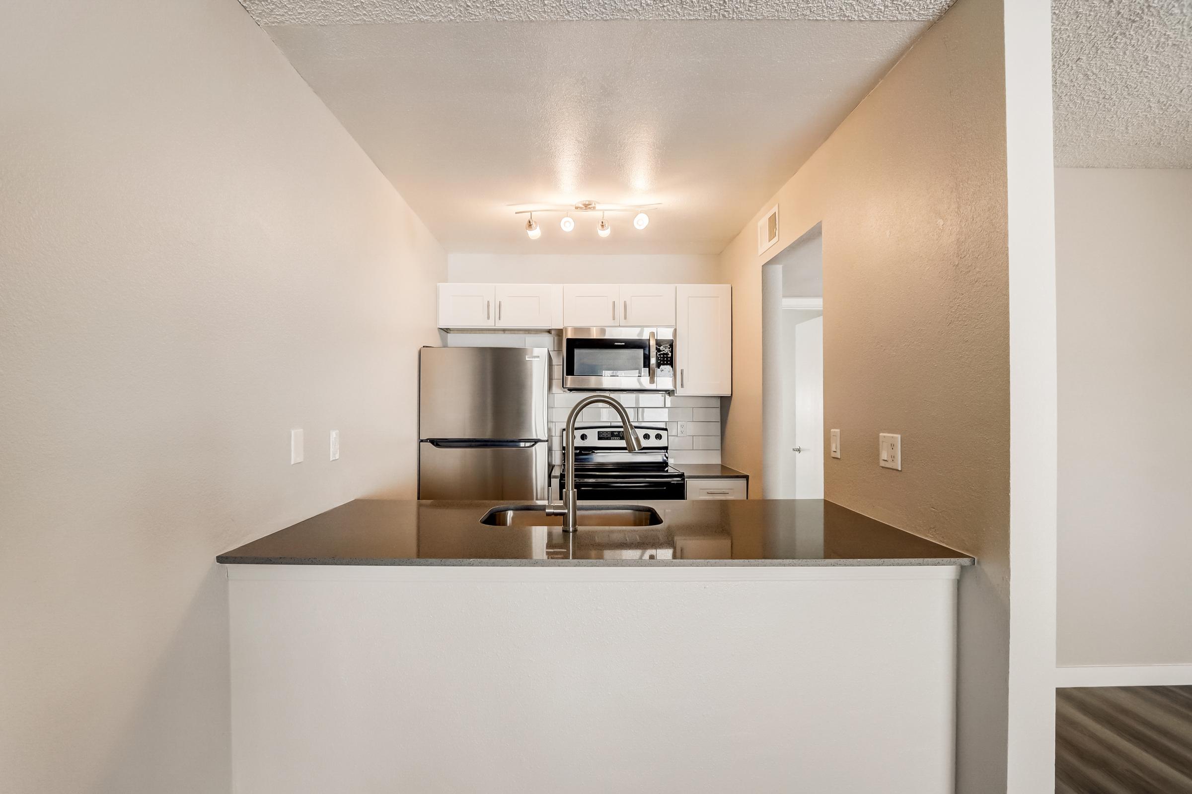 A kitchen with a sink and a refrigerator at Rise at the Lofts.