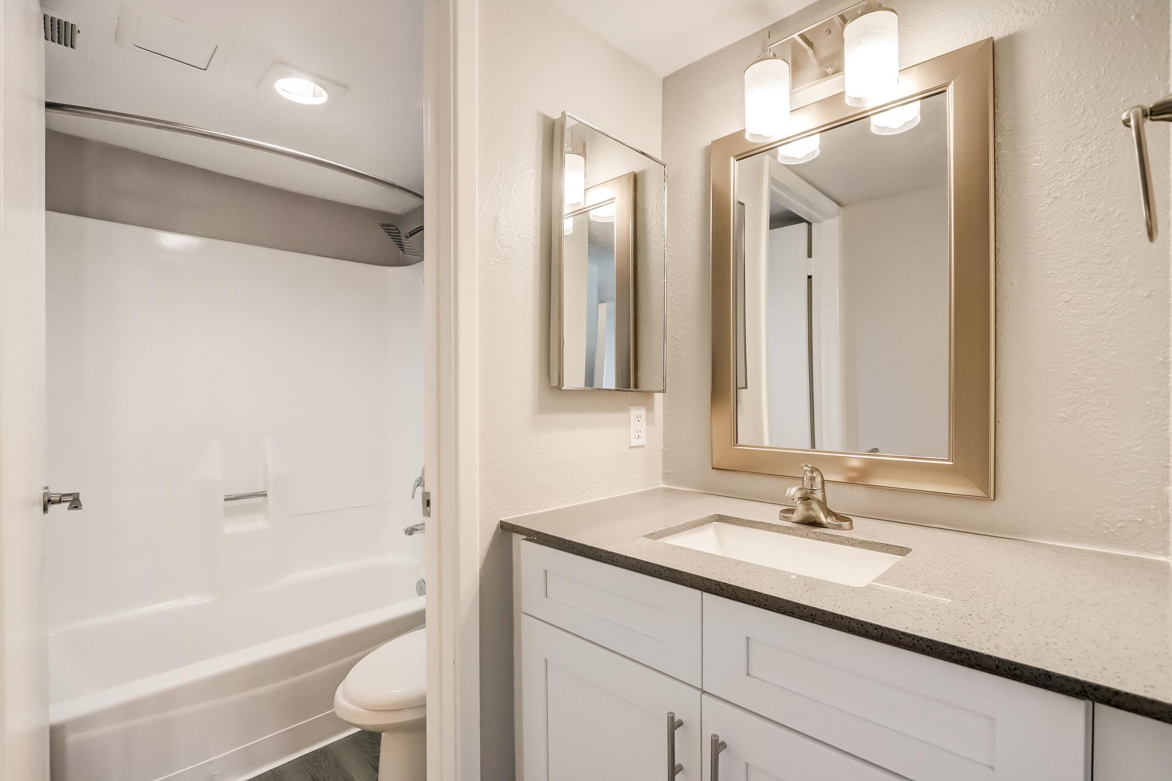 A bathroom at Rise at the Lofts with a vanity, sink and a separate room with a bath. 