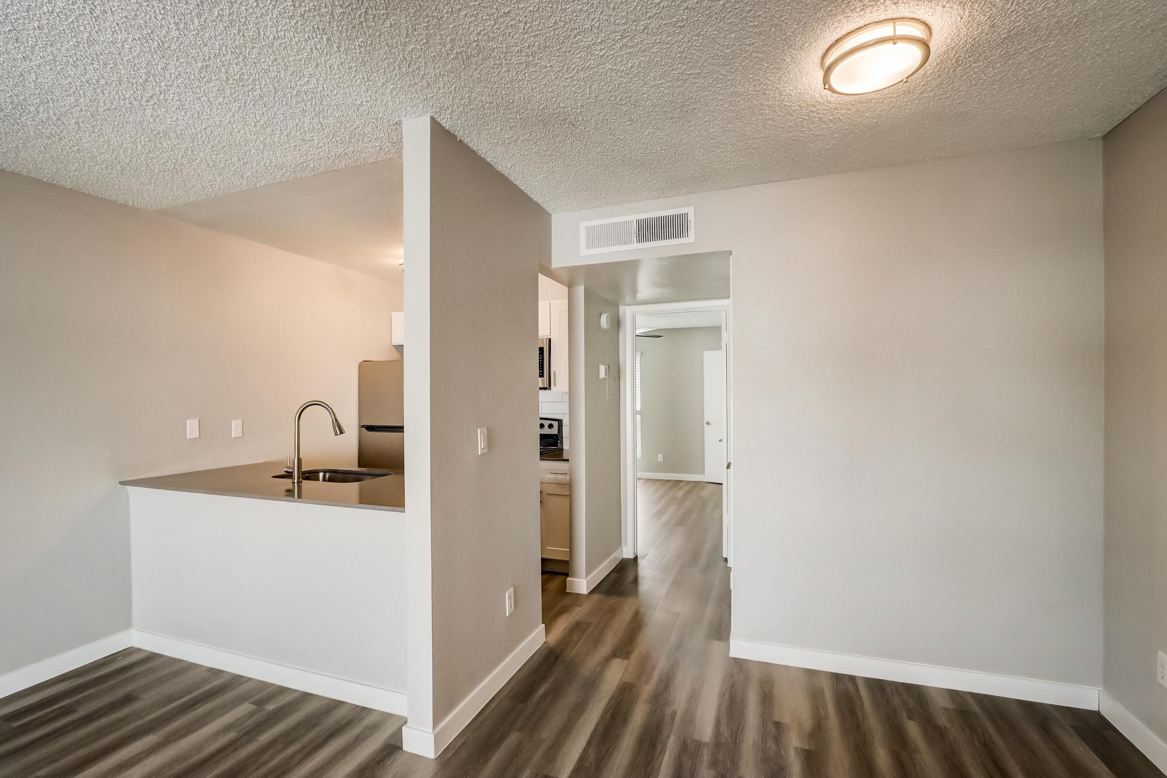 A kitchen and living area with wooden floors at a Rise at the Lofts apartment. 