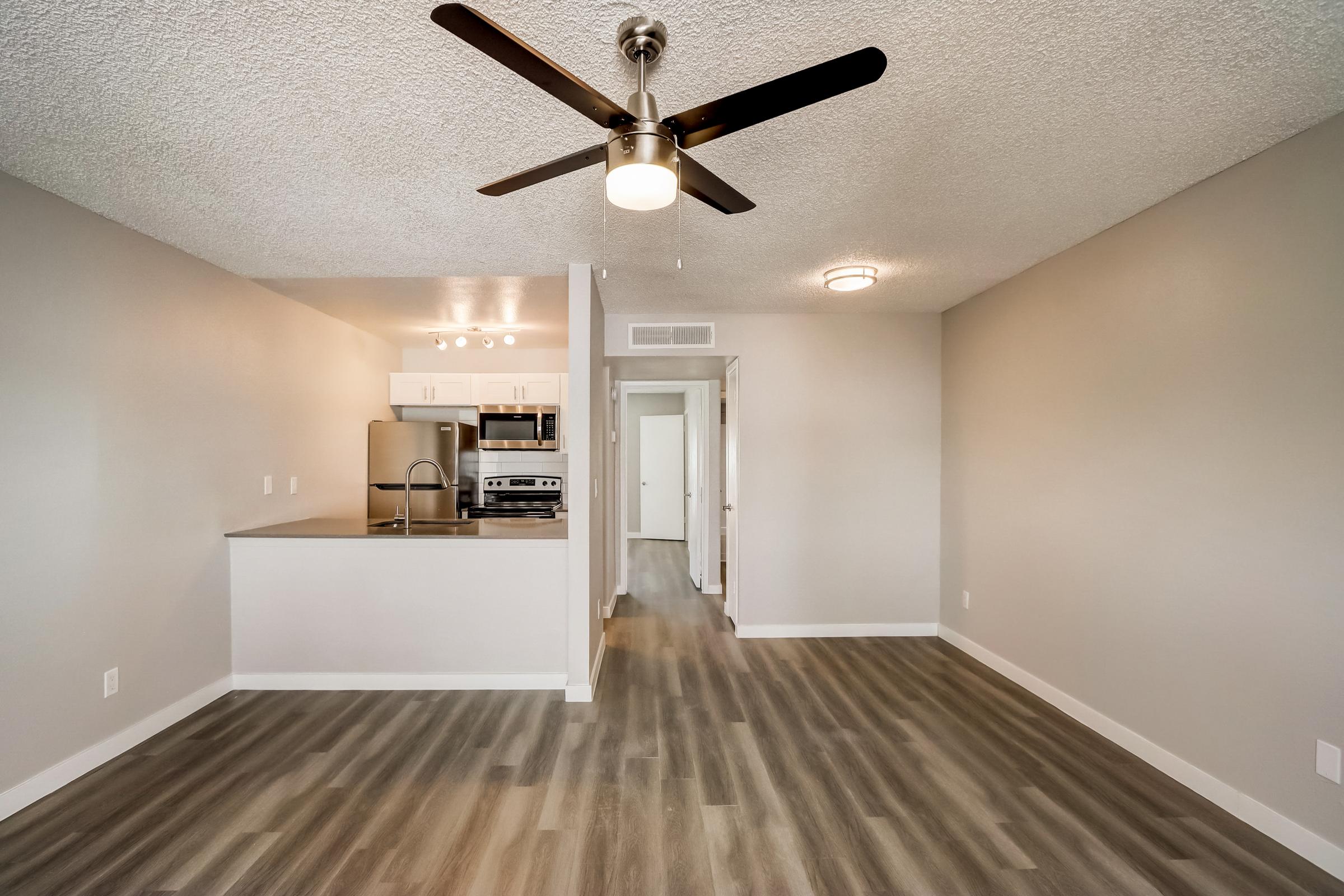 A living room with wood-style floors and kitchen at Rise at the Lofts. 