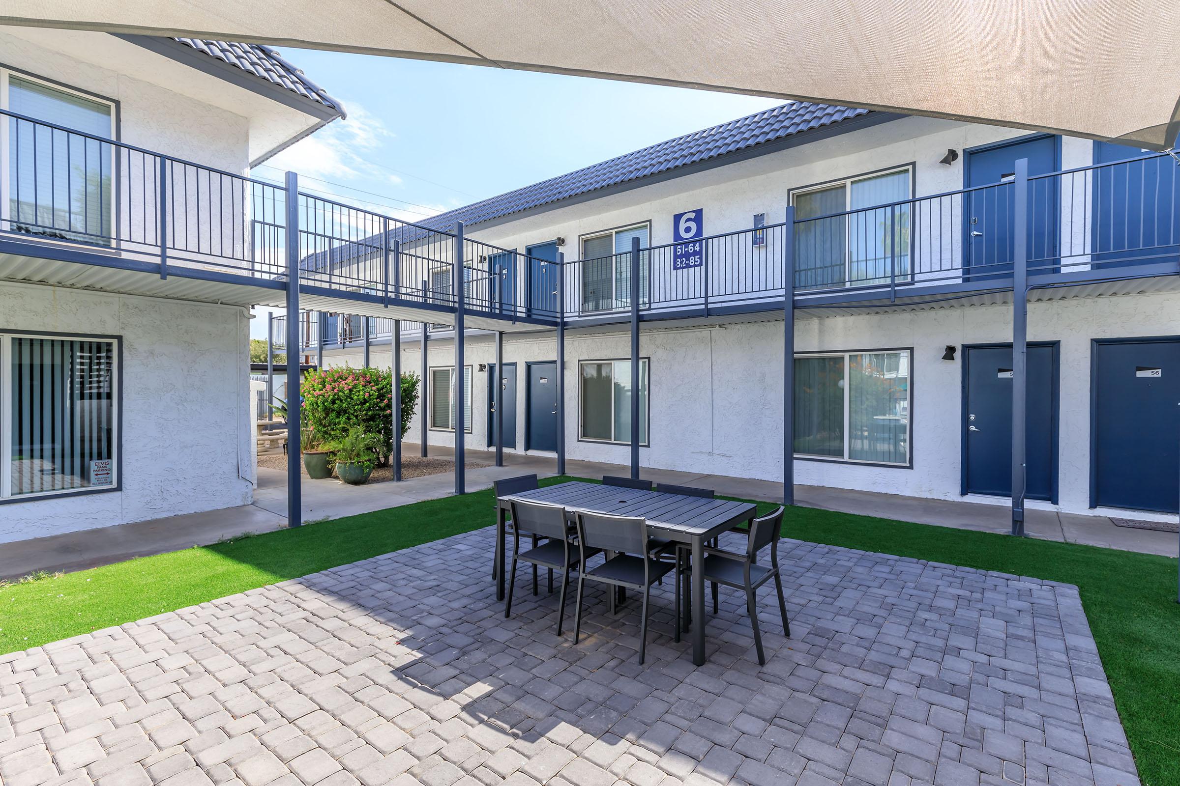 An outdoor patio with table and chairs in a courtyard at Rise at the Lofts.