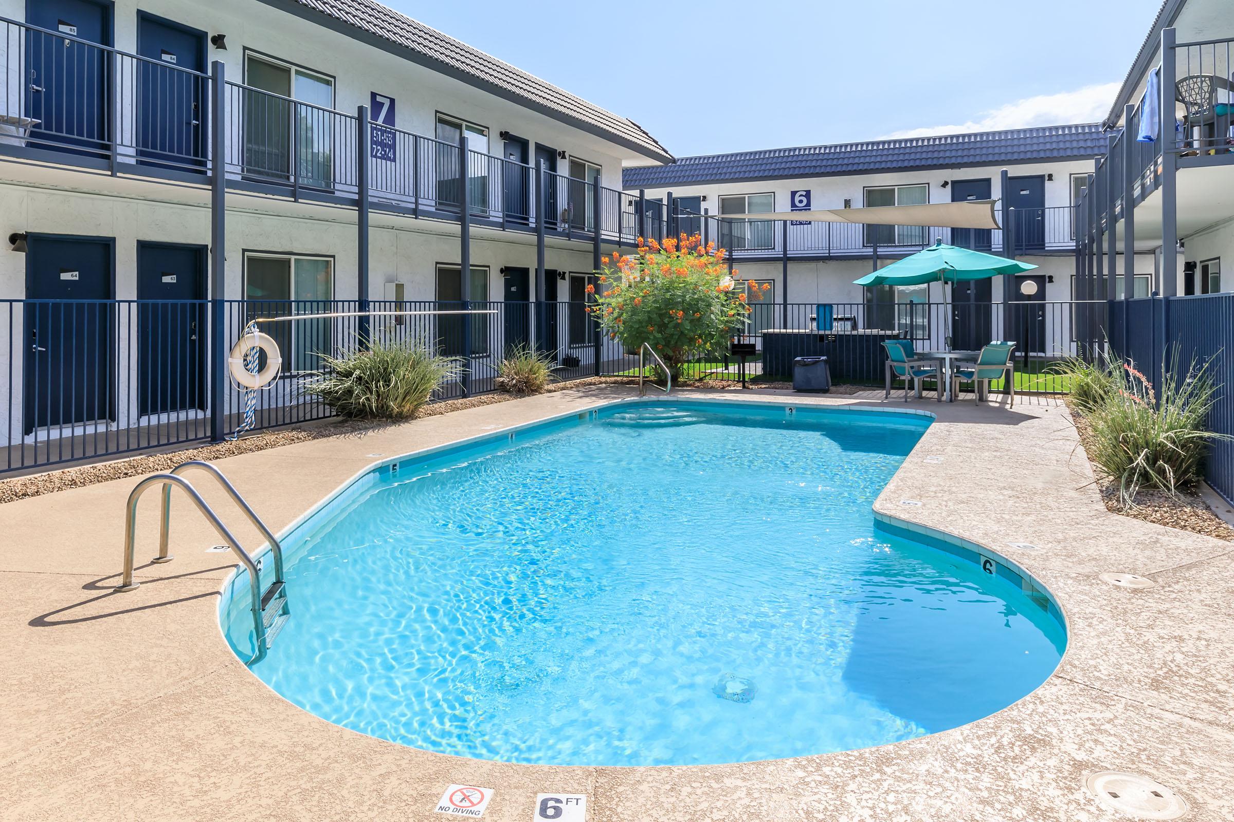 Large blue swimming pool surrounded by apartment buildings at Rise at the Lofts.