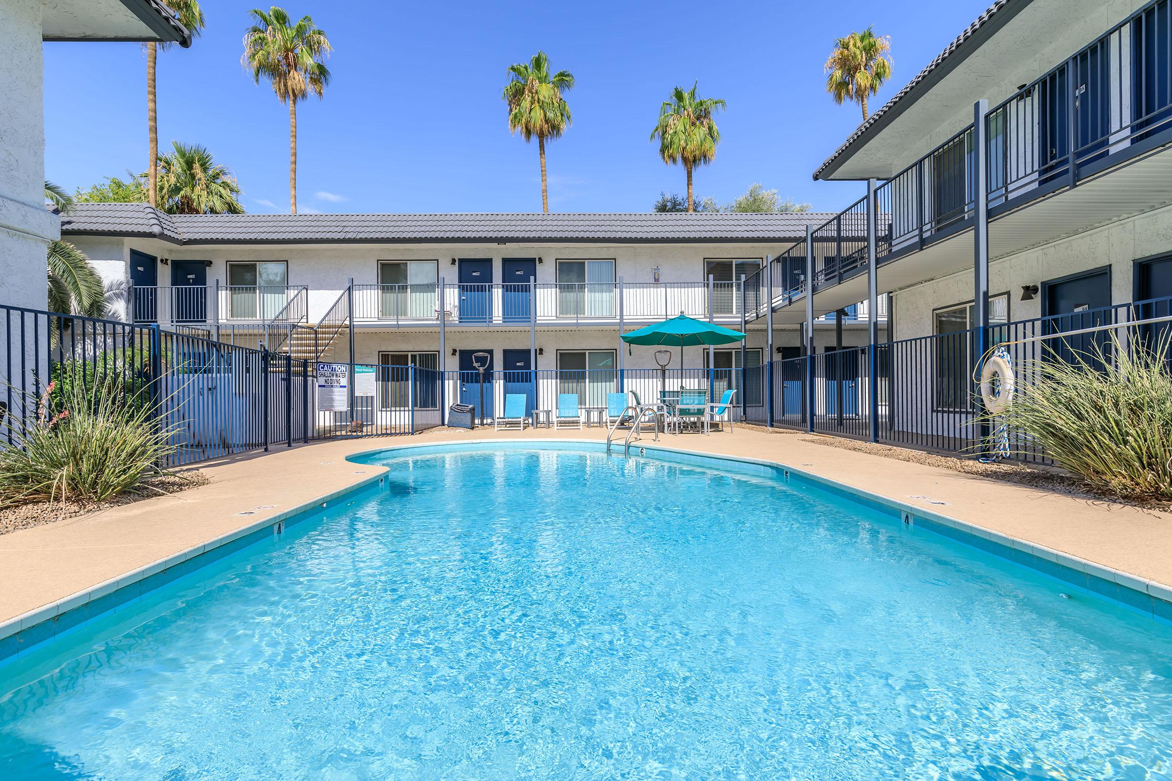 Large blue swimming pool surrounded by pool chairs at Rise at the Lofts