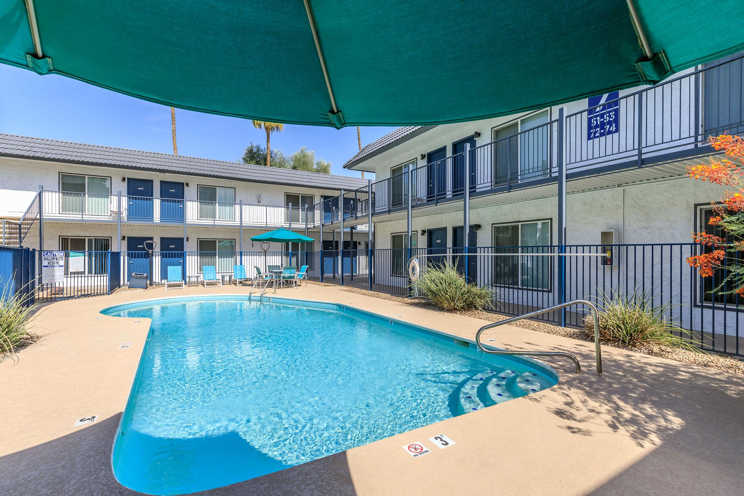 A sparkling blue swimming pool with loungers at Rise at the Lofts. 