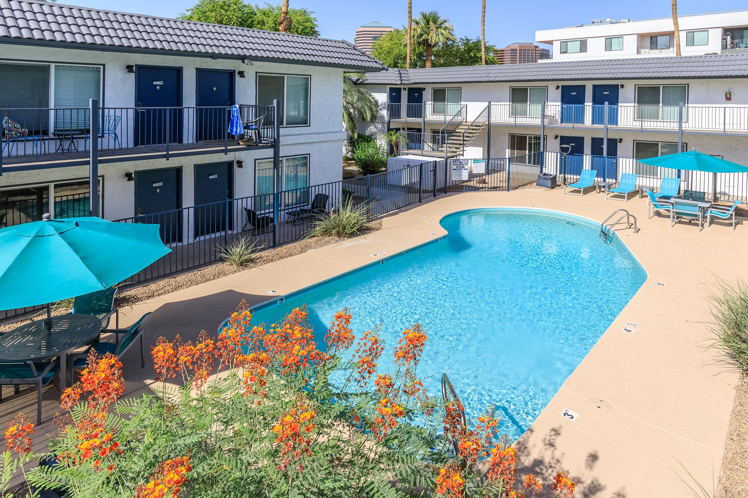 Blue swimming pool surrounded by 2 story apartment buildings