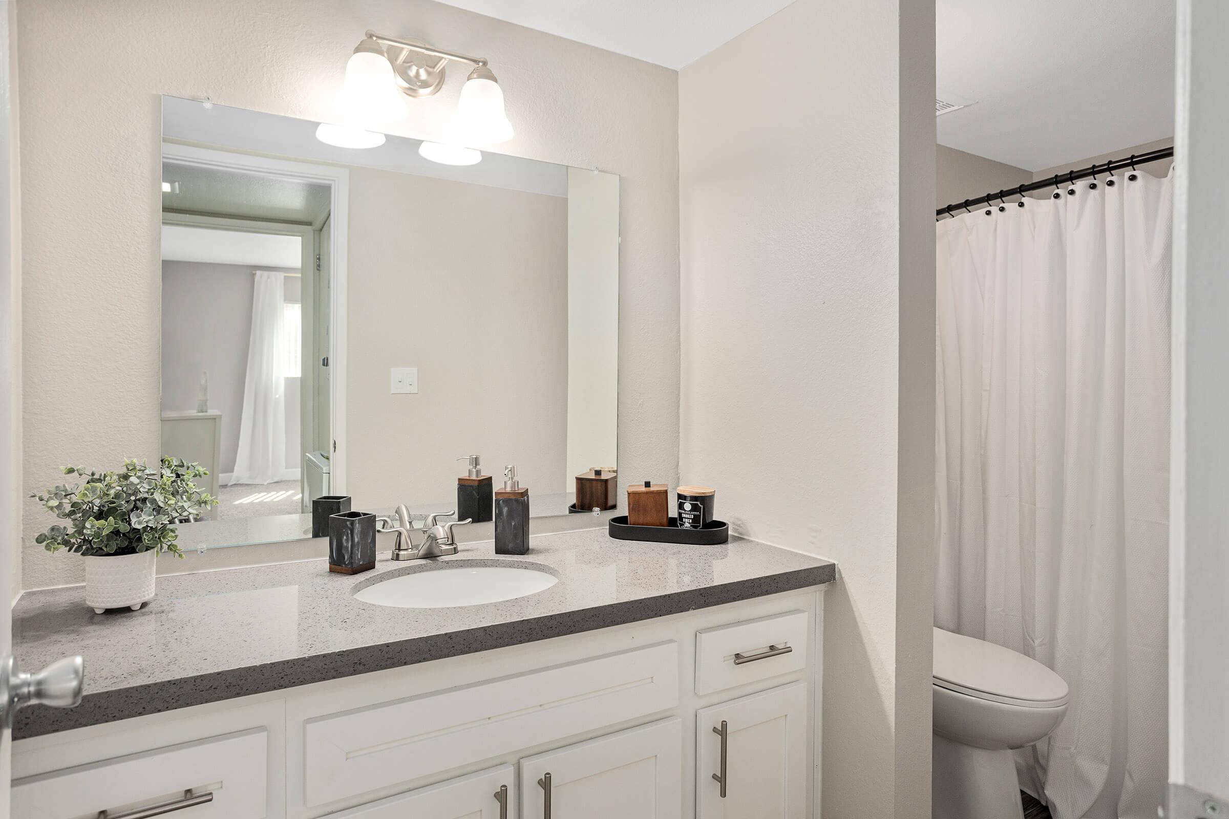 Bathroom quartz countertop vanity with large mirror above.
