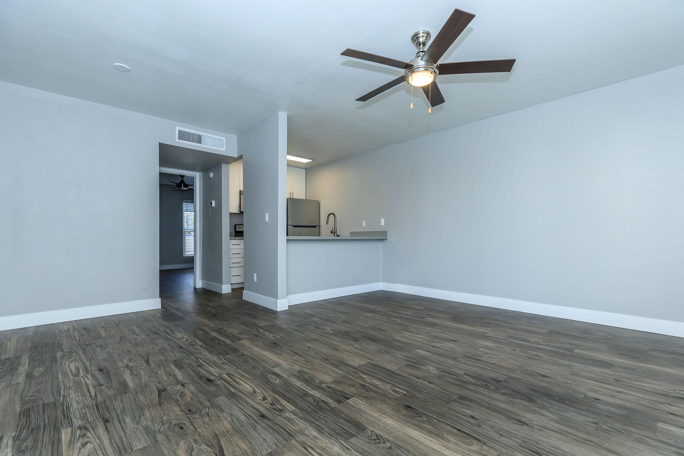 Large open floor plan living room with ceiling fan and view of a kitchen at Rise at the Lofts