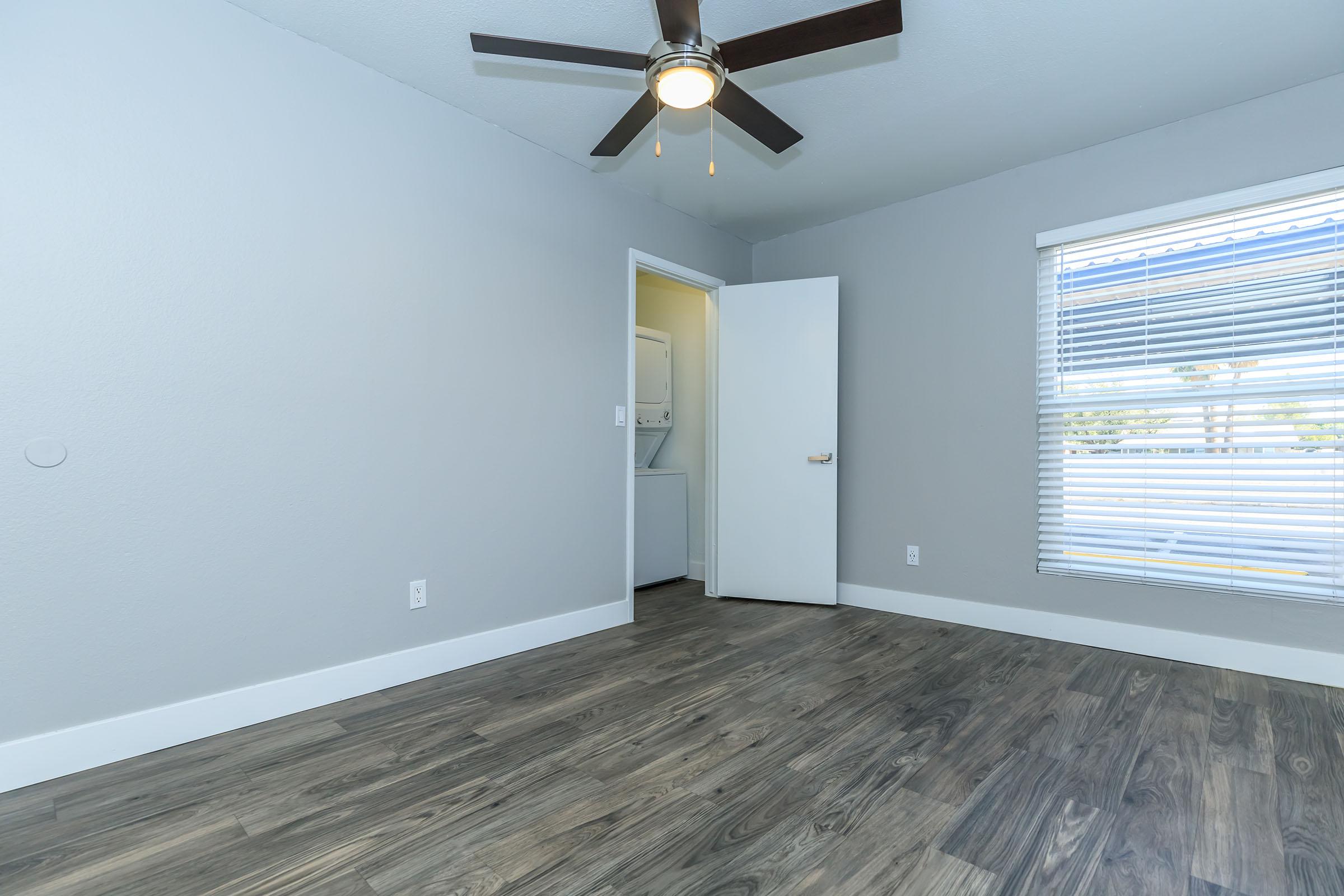 Rise at the Lofts modern bedroom with large window, washer and dryer in a closet, and ceiling fan.