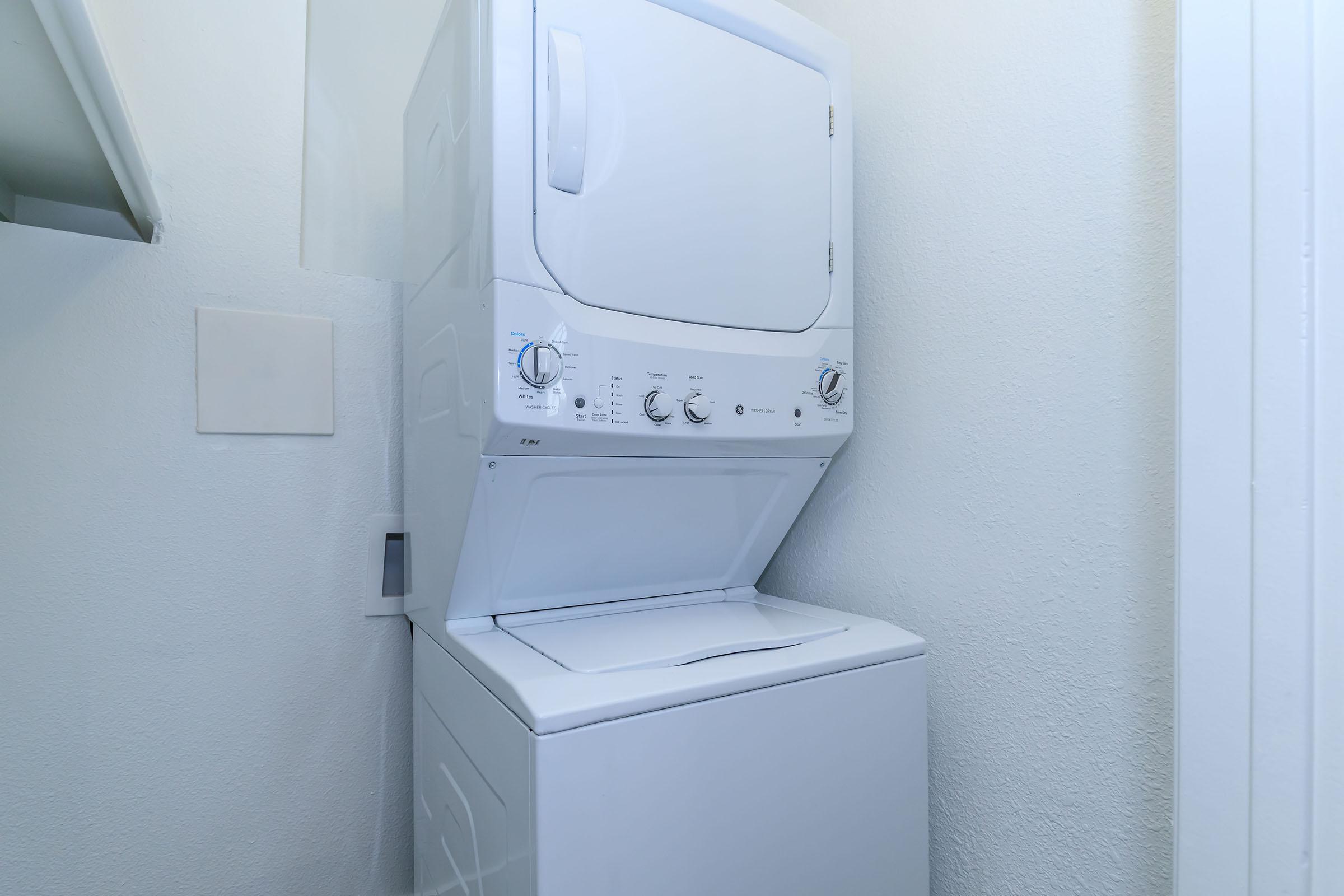 A Rise at the lofts stacked washer and dryer in a laundry room. 